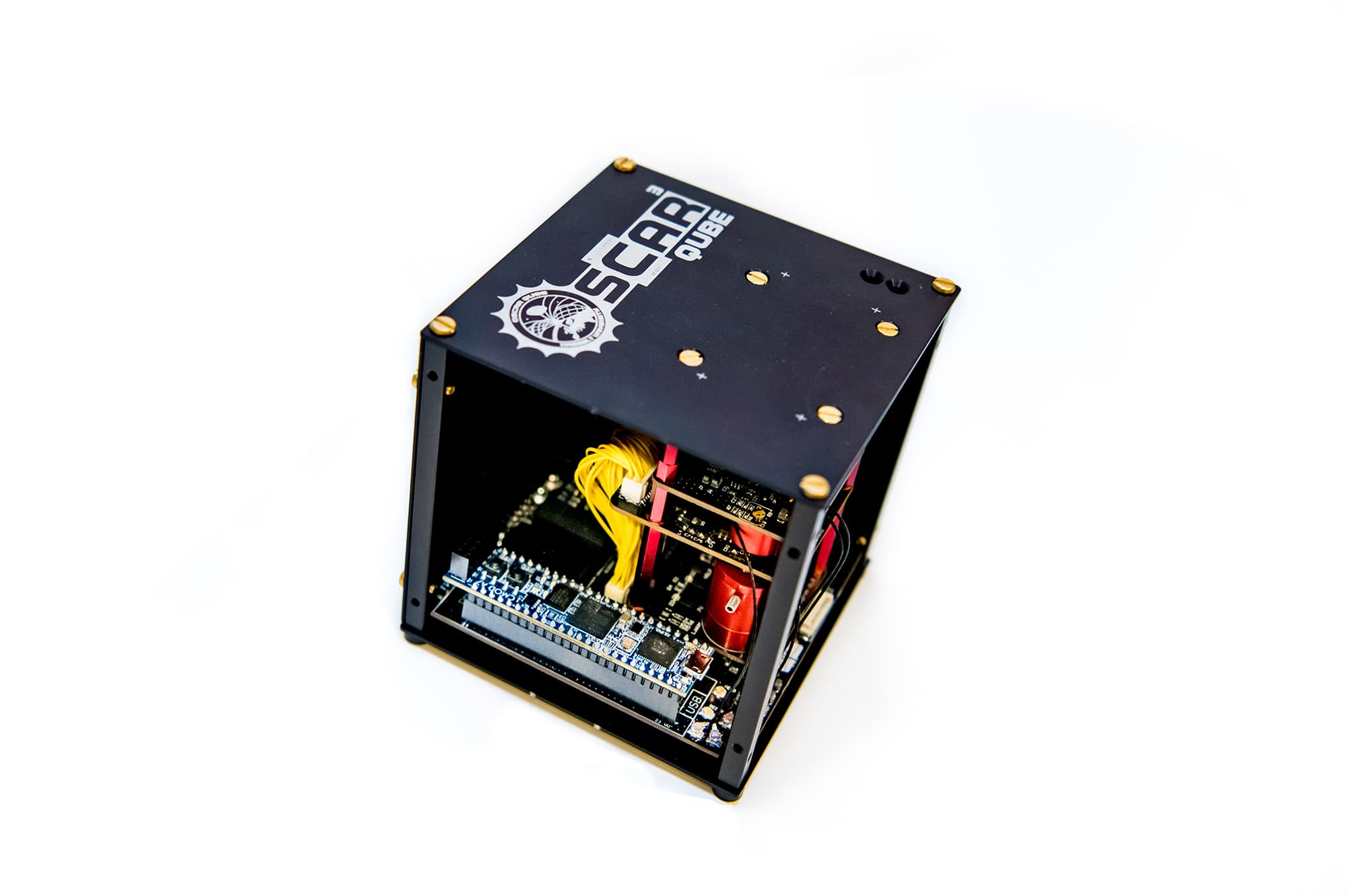 OSCAR-QUBE-2 Klein zwart OSCAR QUBE-apparaat met blootliggende printplaten en gele bedrading op een witte achtergrond