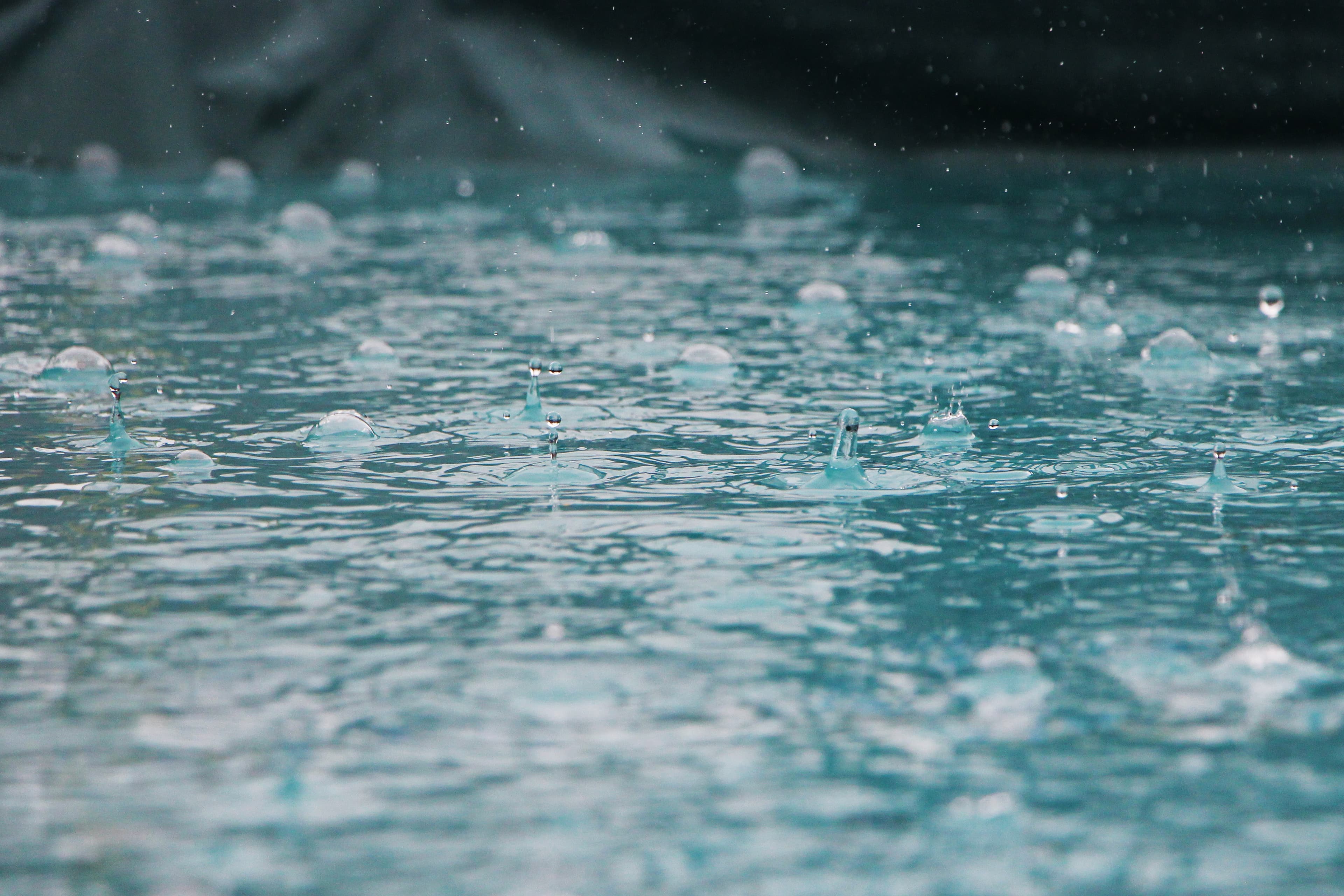 Overstroming%20regen Regendruppels die op een wateroppervlak spatten, wat op zware regenval en overstromingen wijst