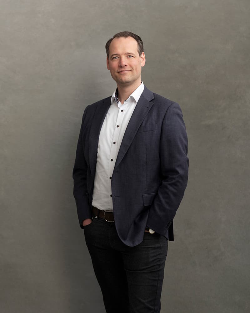 Patrick-van-Deursen Patrick van Deursen standing in a dark blazer against a gray studio backdrop