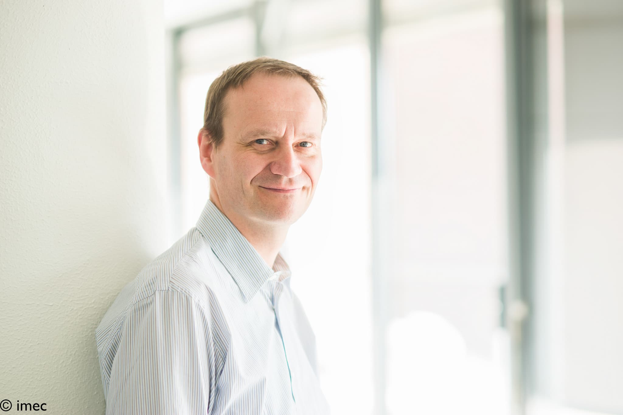 paul-heremans_header_1 Portrait of researcher Paul Heremans standing in a bright hallway