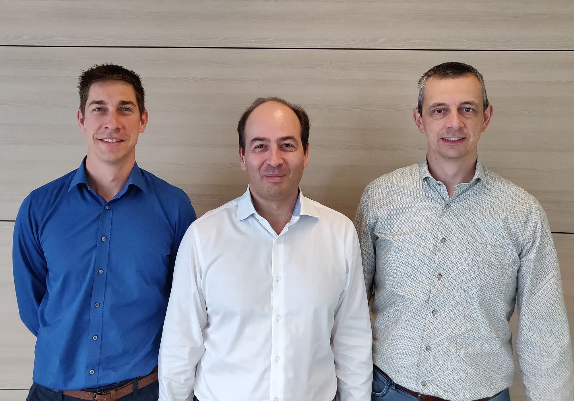 persbericht-06-09-2018_0 Three men standing side by side in front of a plain wall, posing for a company announcement