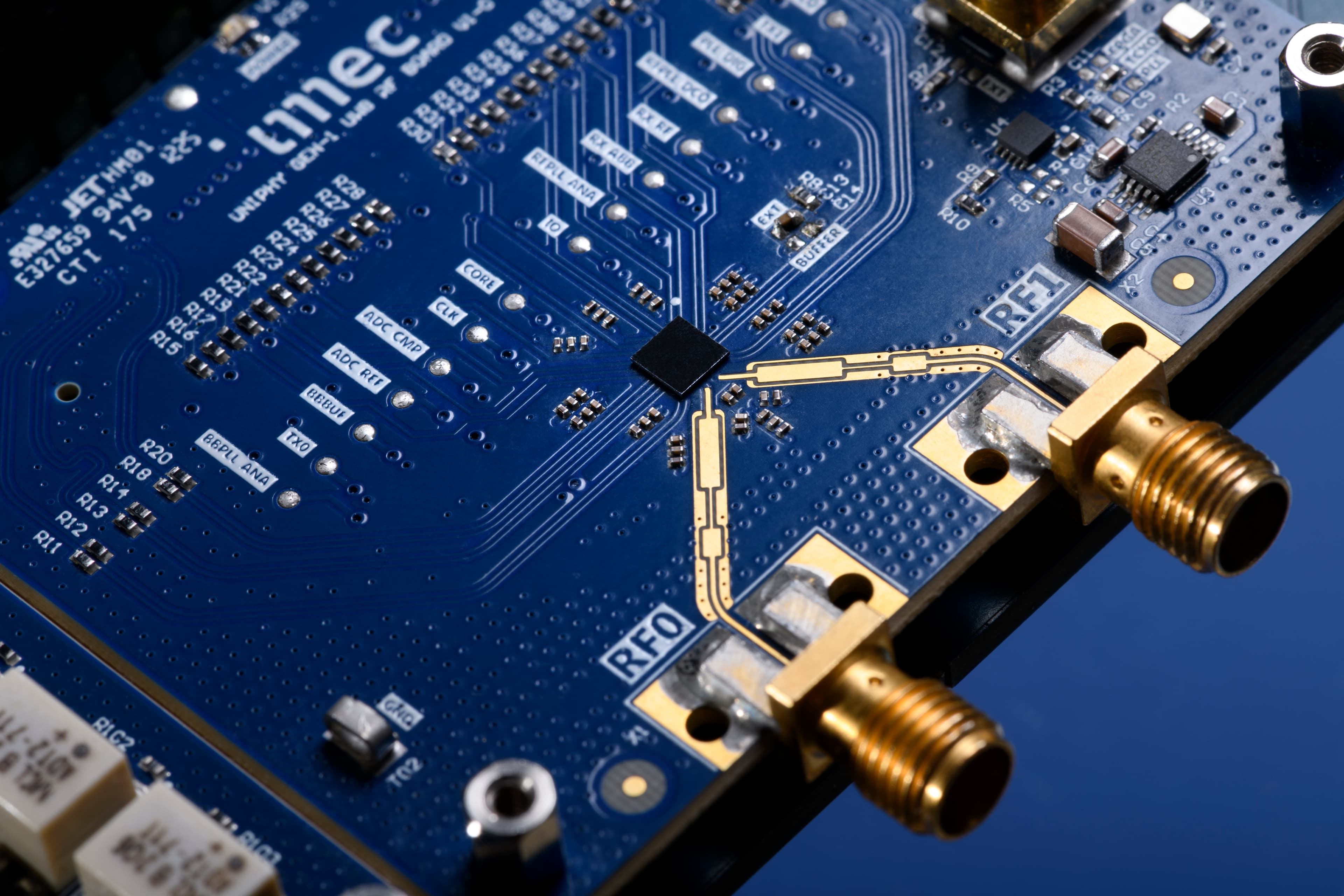 Close-up of blue RF circuit board with connectors and central chip Close-up of a blue RF circuit board with gold connectors and a central chip