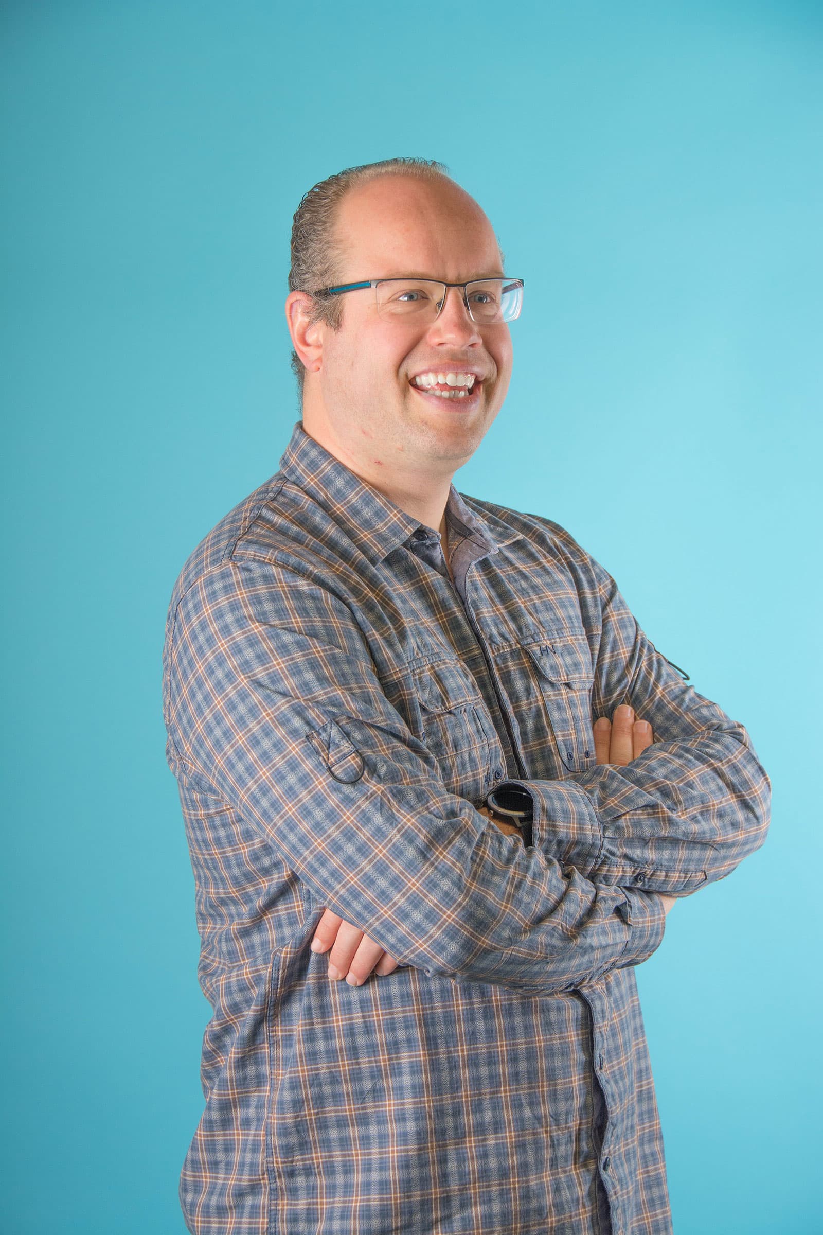 portrait of man smiling with arms crossed Portrait of Marcel Zevenbergen smiling with arms crossed against a blue background