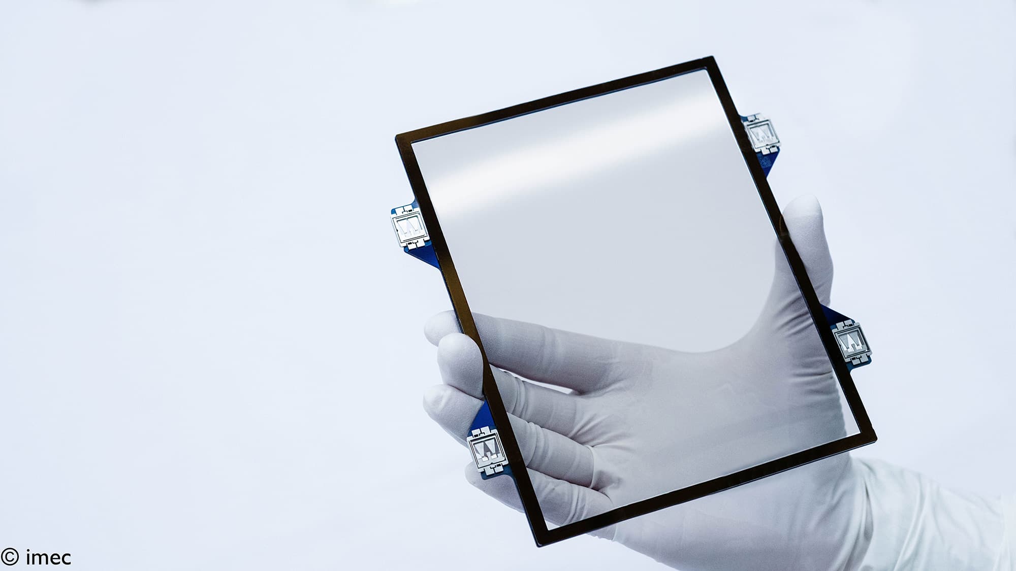 photo-pellicle_copyright Gloved hand holding a square CNT pellicle frame with a transparent center and mounting tabs