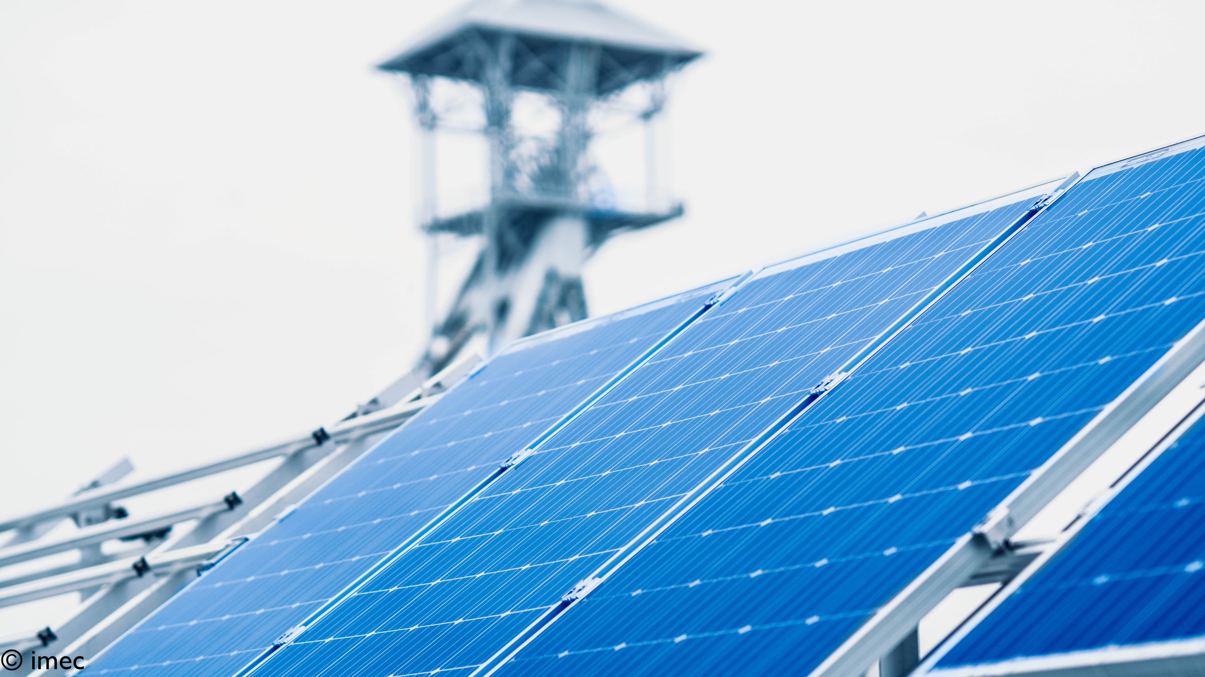 Photovoltaics-%28incl-thin-film%29-2021-005 Schuingeplaatste zonnepanelen met een wazige toren op de achtergrond
