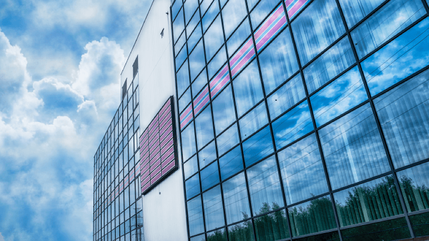 modern glass building facade with pink louvers Modern glass building façade with reflective windows and pink horizontal louvers against a blue sky