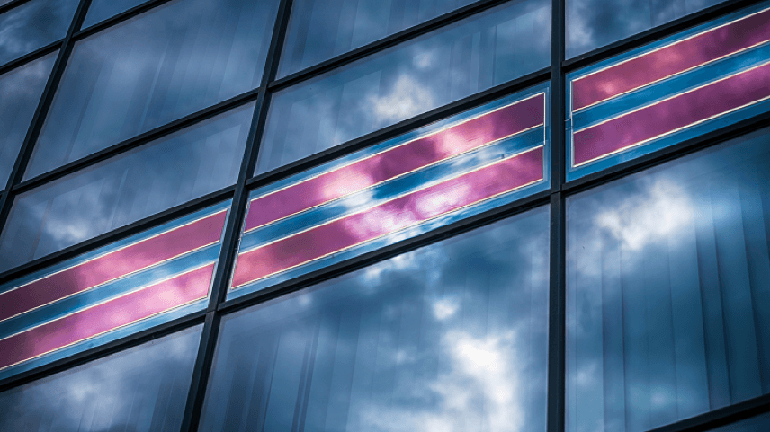Glass building façade with pink solar panels Glass building façade with integrated pink solar panels reflecting the sky