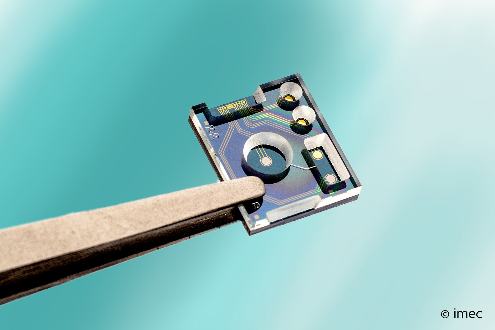 Prototype-low-power-intergrated-liquid-sensor_0 Prototype liquid sensor chip held by tweezers against a blue background