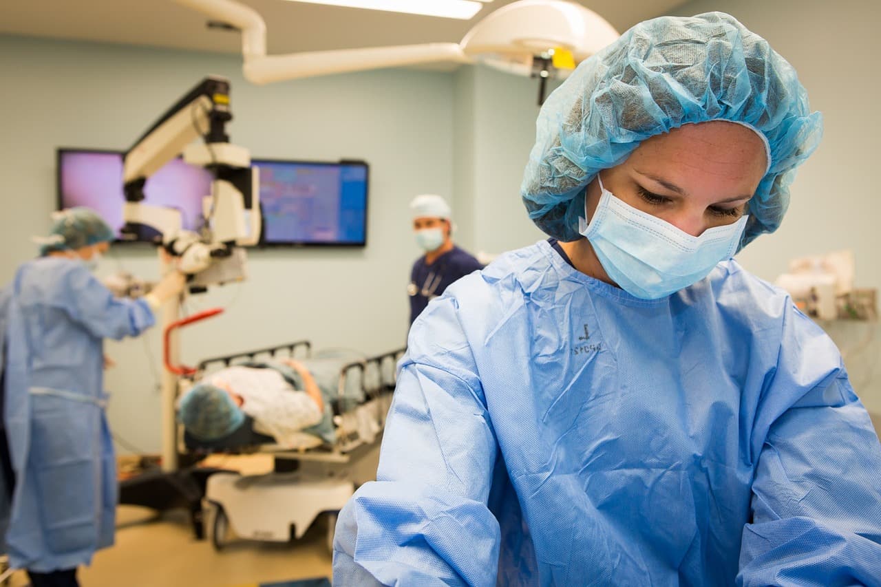 Surgeon in operating room Surgeon in blue scrubs and mask in an operating room with surgical equipment in the background