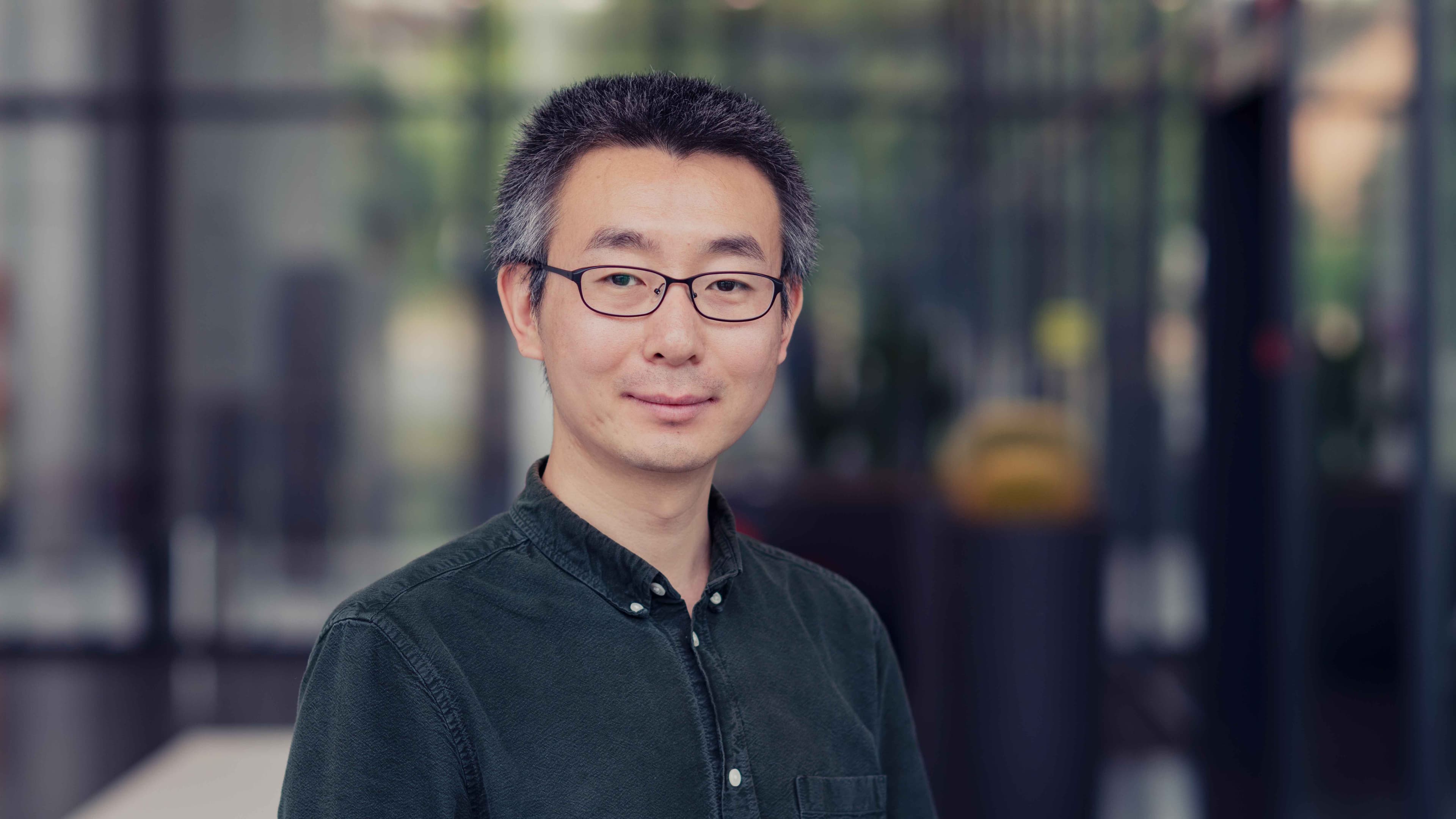 Ruoyu%20Li Portrait of Ruoyu Li, senior researcher at imec, wearing glasses and a dark shirt in a blurred indoor setting.