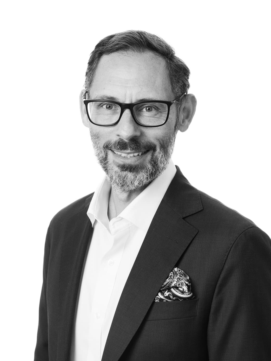 Sandi%20Habinc Portrait of Sandi Habinc in a suit and glasses, smiling against a white background