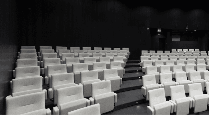 empty lecture hall with gray seats Empty lecture hall with rows of light gray seats and dark walls