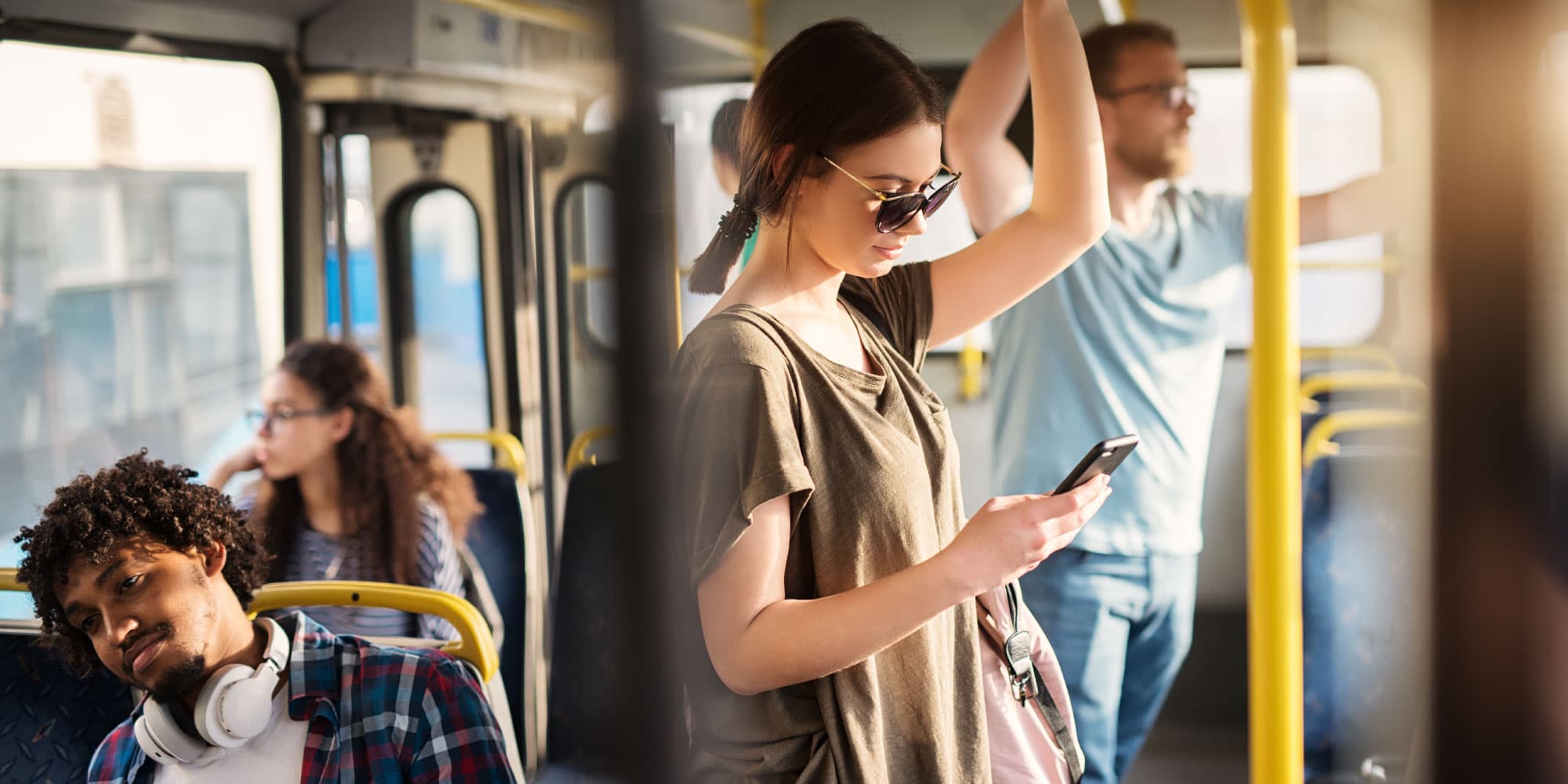 SCM Passagiers die staan en zitten in een stadsbus, een vrouw die haar telefoon bekijkt