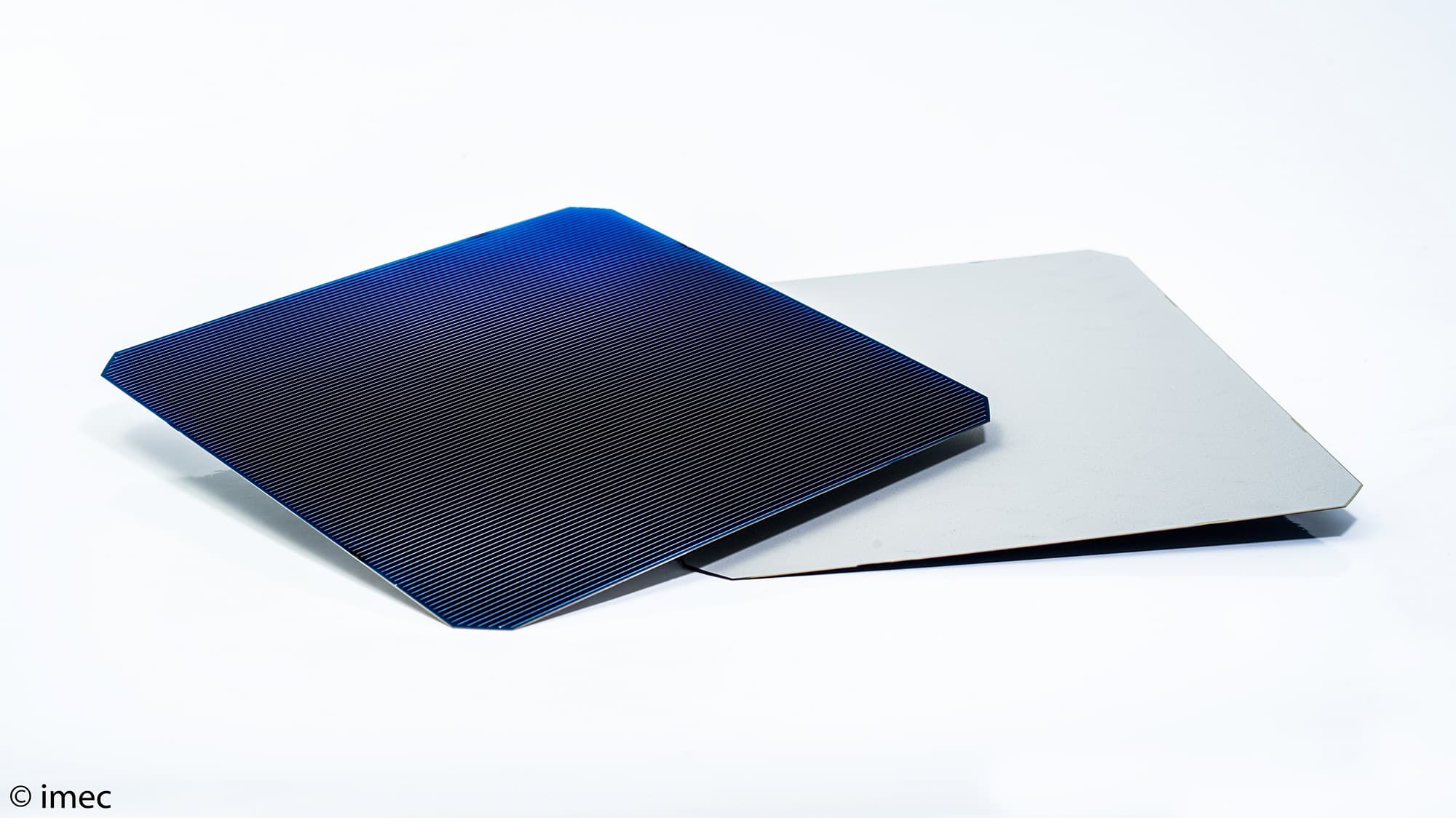 screen-printed-bifacial-and-monofacial-solar-cells002_low_0_0 Two large solar cells, one dark blue and one silver, overlapped on a white background