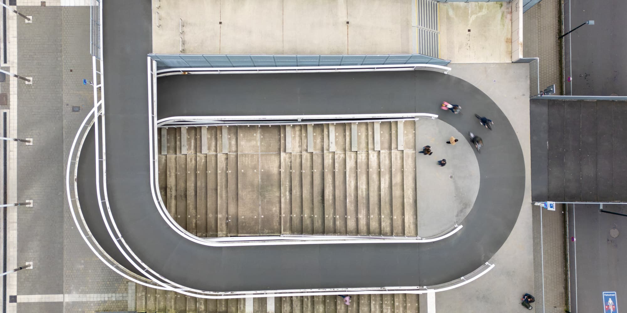 Slimme-stadsdistributie Overhead view of a pedestrian ramp and stairs between city streets, with a few people walking below