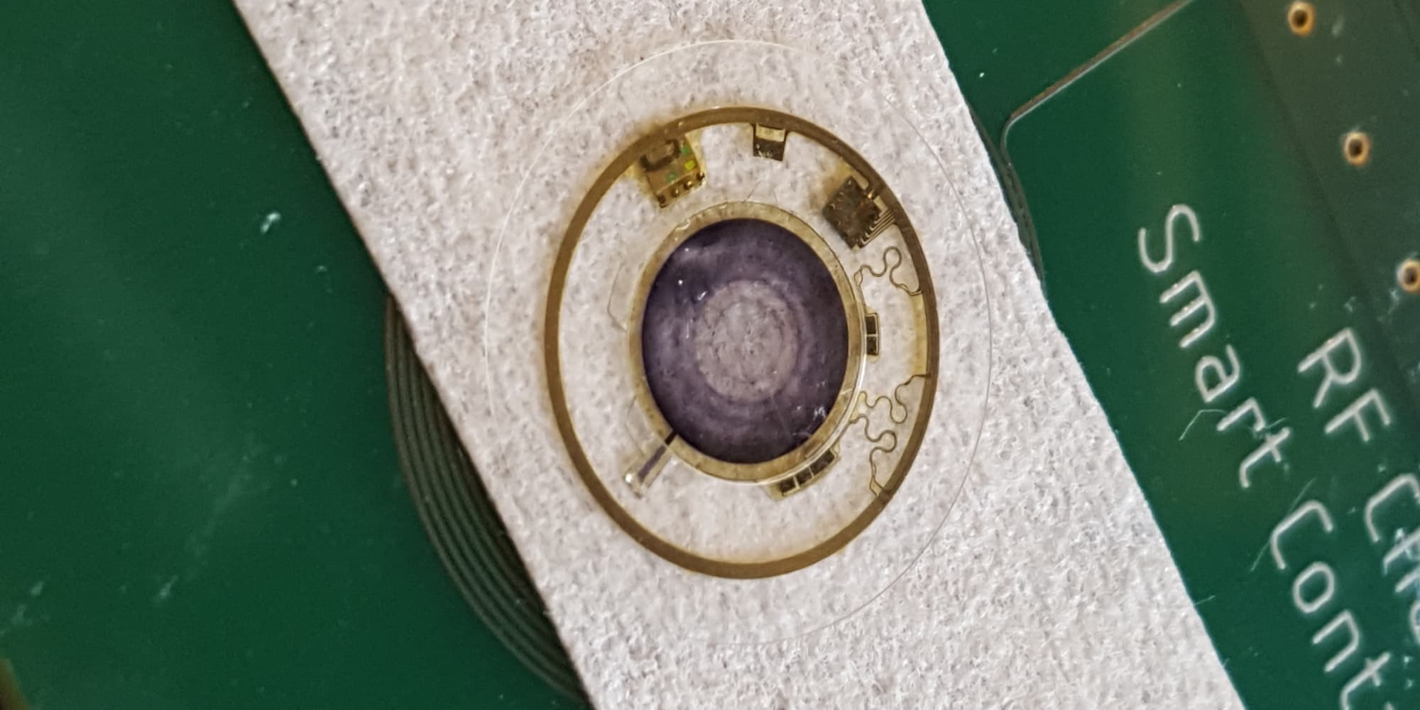 Smart-Contact-Lens-Mimicking-the-Human-Iris Slimme contactlens met een cirkelvormig elektronisch irispatroon op een groene printplaat