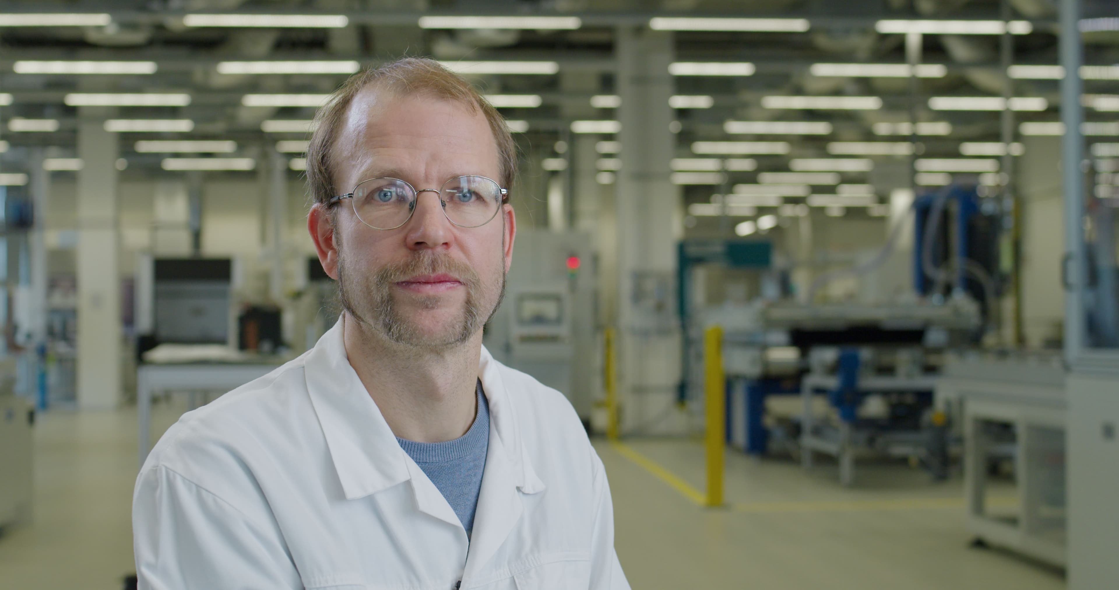 SNROOF_jonathan_01 Jonathan Govaerts in a cleanroom-style lab wearing a white coat and glasses