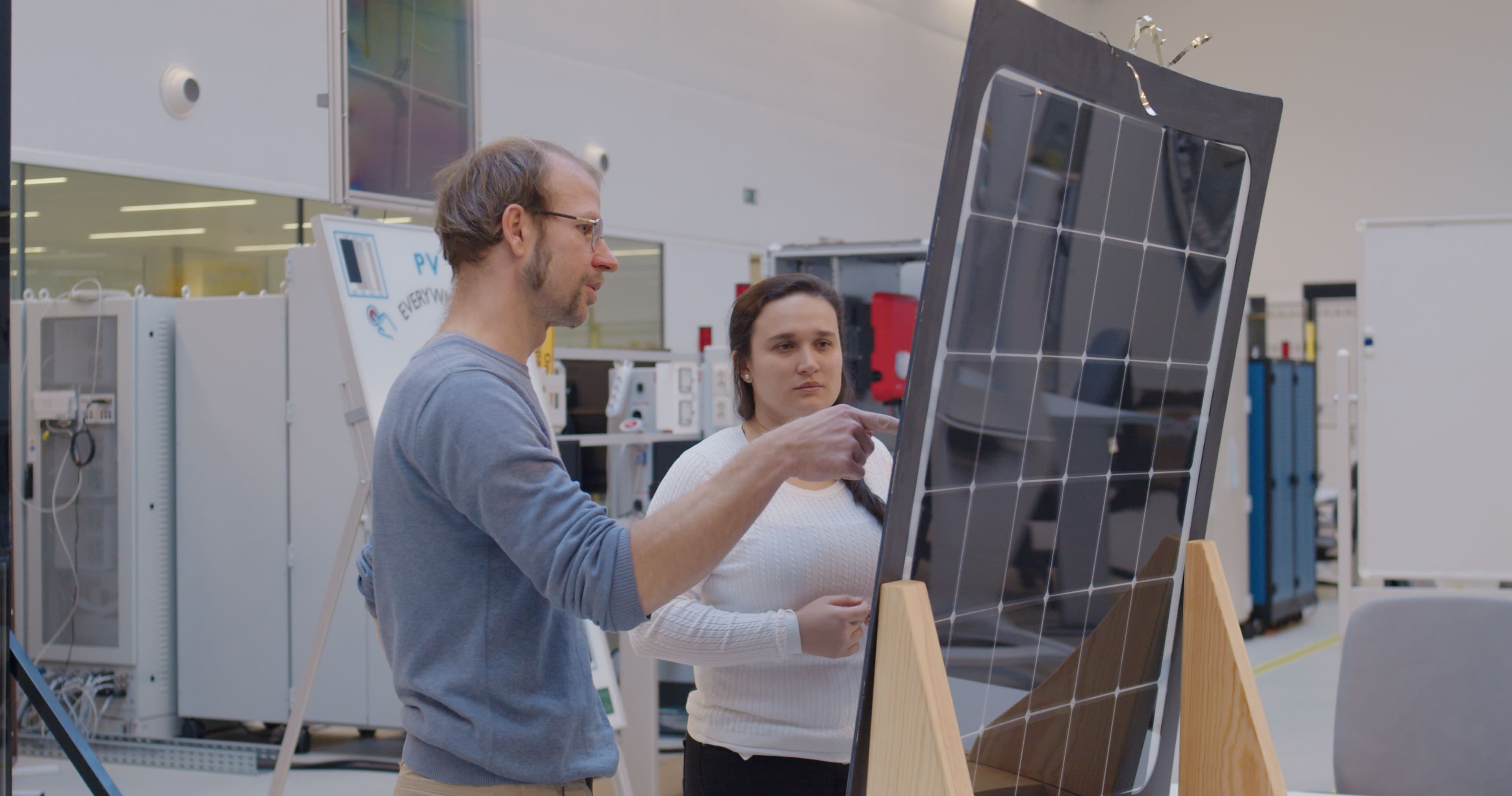 SNROOF_zonnepaneel_02 Two researchers examine a curved glass solar panel in a laboratory.