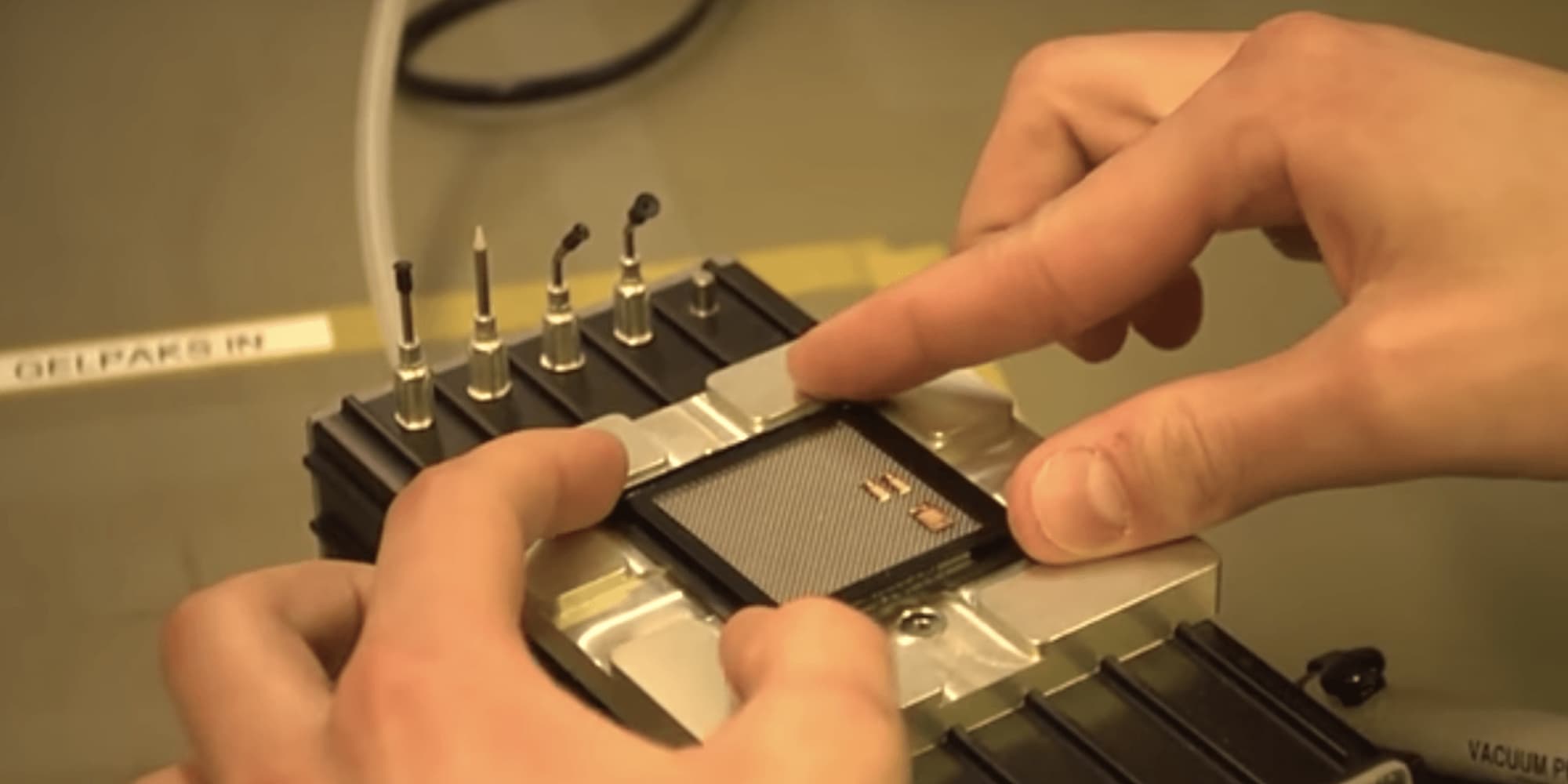 Hands positioning chip in lab fixture Hands positioning a small chip or wafer in a lab fixture beside precision tools