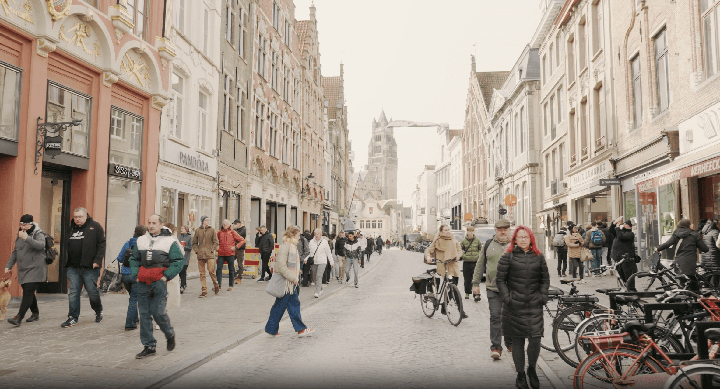 StadBrugge_3 Drukke straat in Brugge met voetgangers, fietsers en historische gebouwen langs de weg