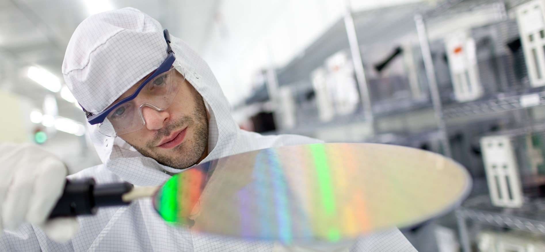 Stay-informed-semiconductor Researcher in a cleanroom examines a reflective silicon wafer