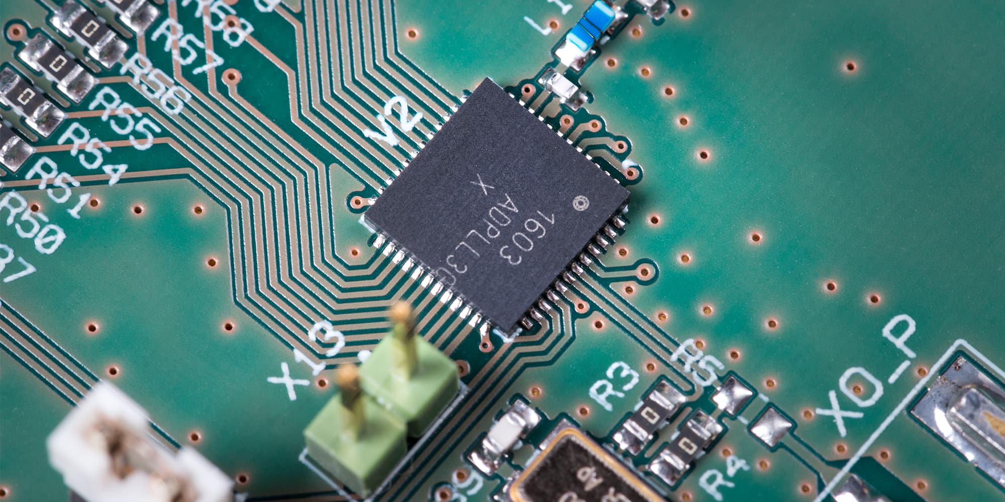 Sub-mWAll-Digital-PLL_low_1 Close-up of a circuit board with a central integrated circuit and fine copper traces