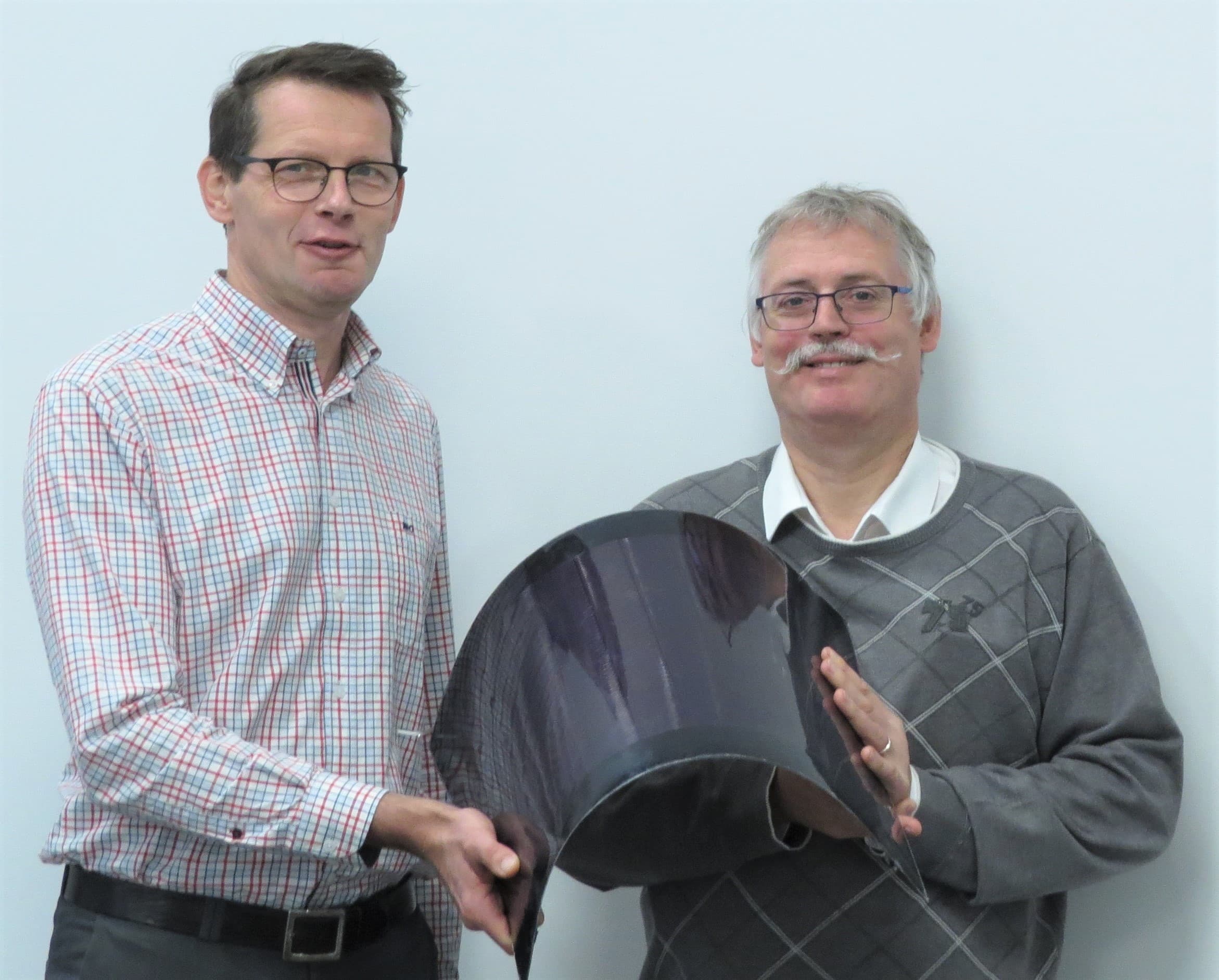 Two men holding flexible solar panel prototype Two men holding a thin, flexible solar panel prototype