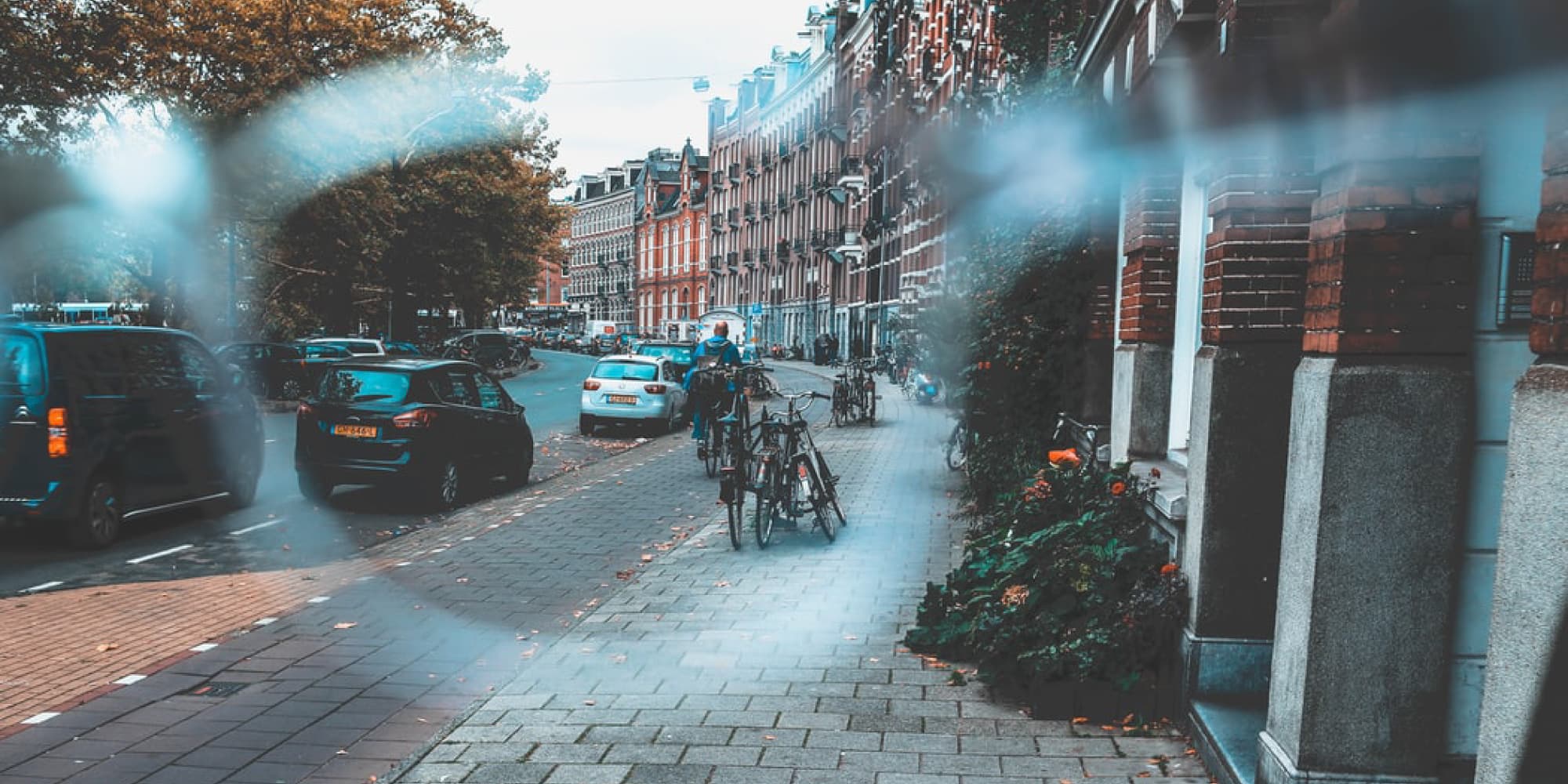 Technologie-en-de-15-minutenstad Stadsstraat met fietsers, geparkeerde auto's en appartementen langs een met bomen omzoomd trottoir