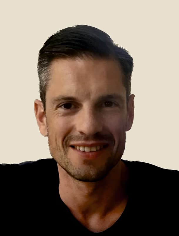Tom%20Borgers Portret van Tom Borgers, glimlachend tegen een effen achtergrond