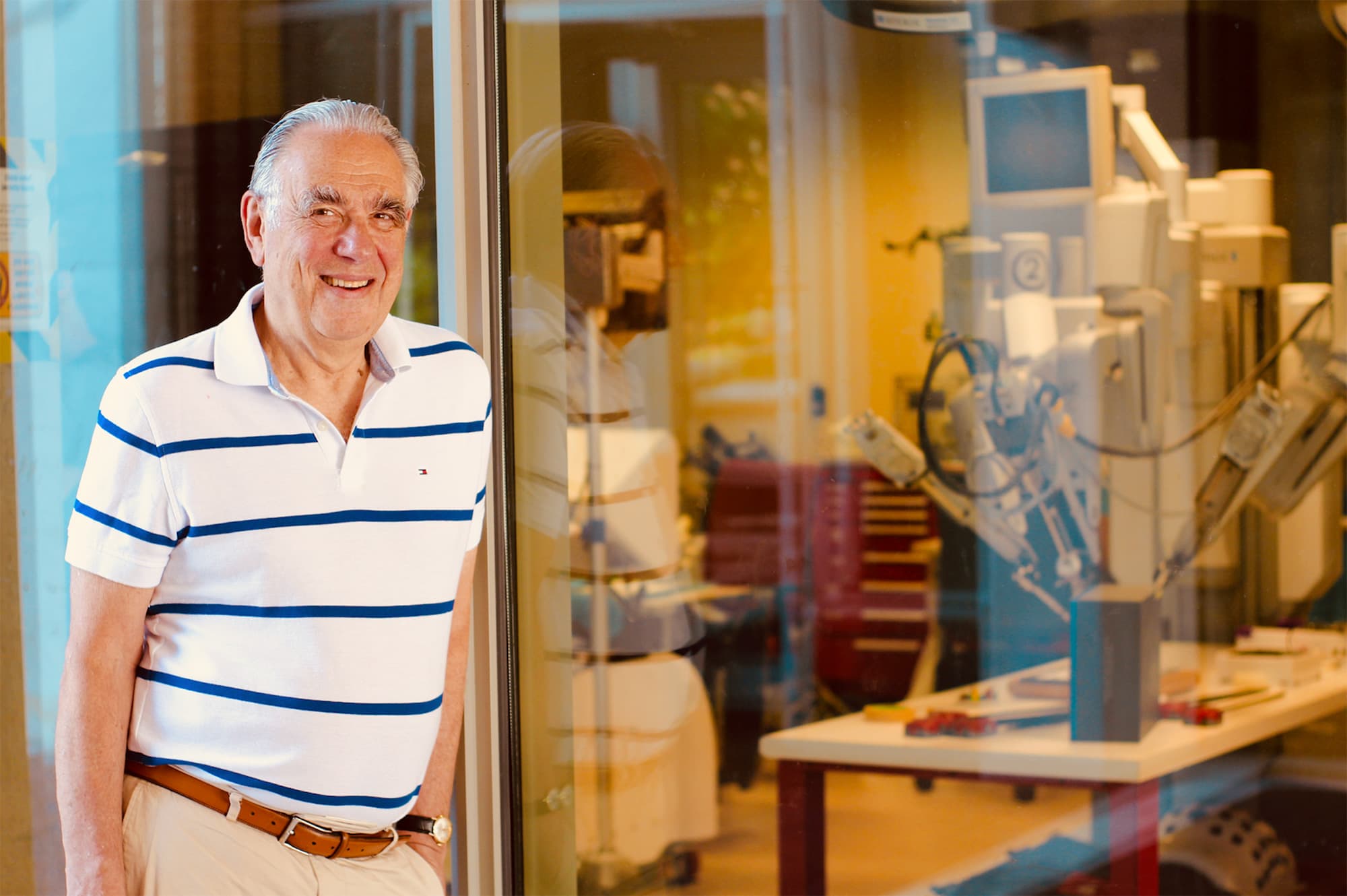 Tom_Fekete_1 Tom Fekete smiling beside a lab window with scientific equipment visible behind the glass