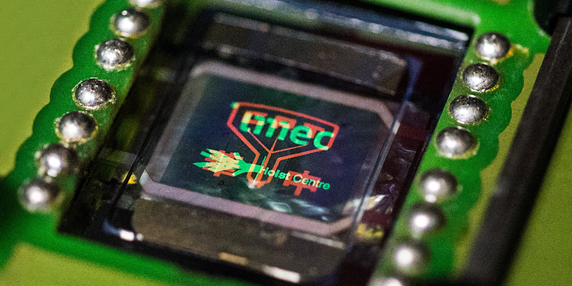 Touch-Taiwan-2017_1 Close-up of an OLED display chip mounted on a green circuit board with imec and Holst Centre logos.
