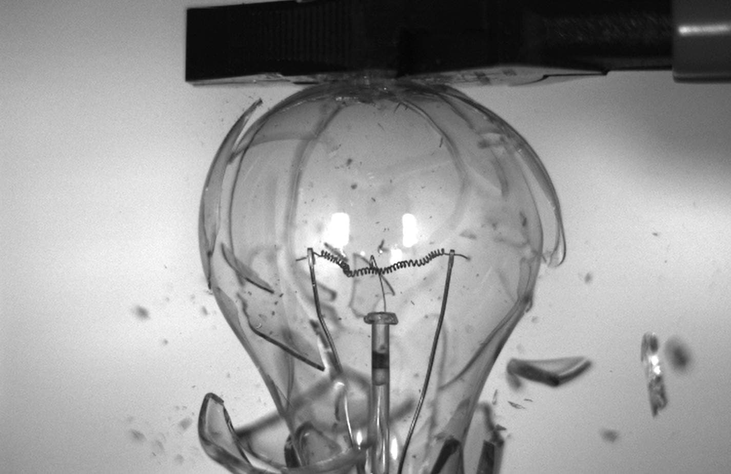 ultra-high-speed%20imaging High-speed black-and-white frame of a light bulb shattering as fragments scatter