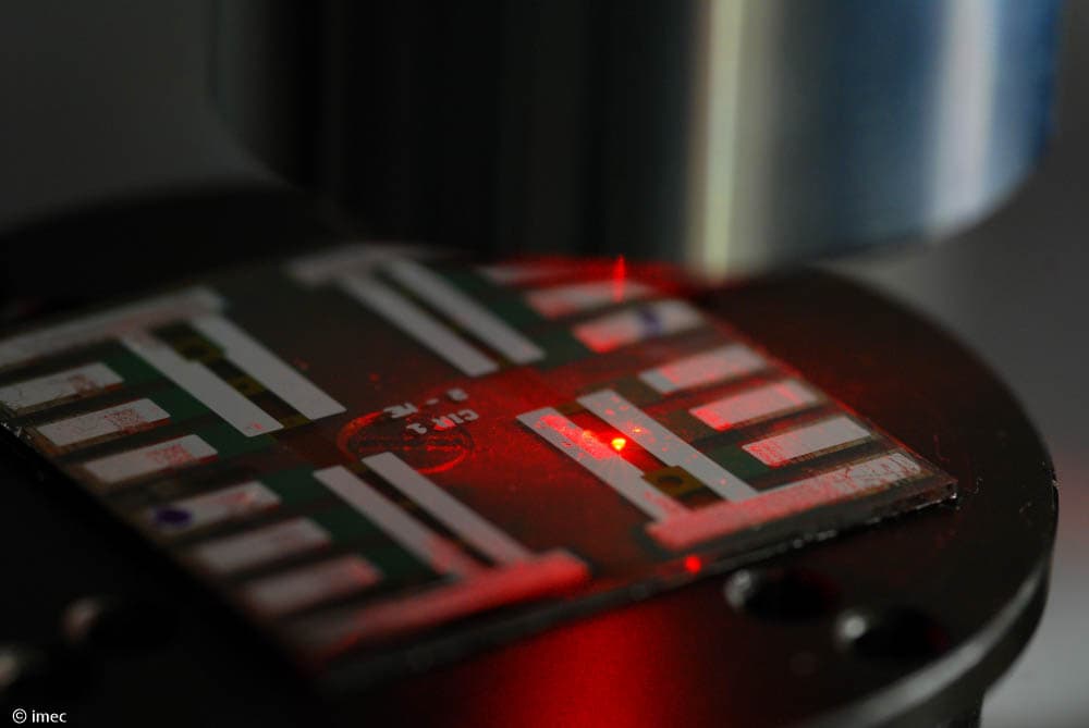 ULTRALUX_0 Perovskite LED device on a substrate emitting red light under a microscope