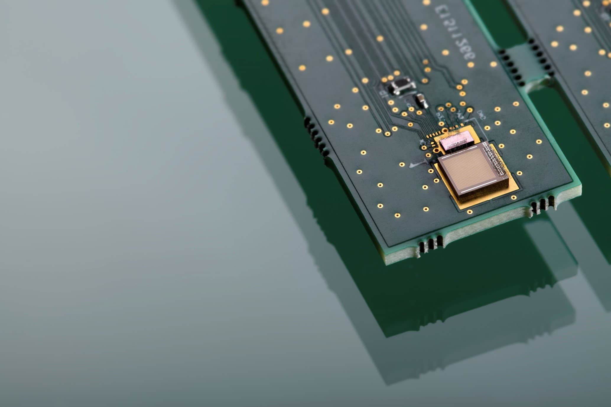 Ultrasound%20powering Close-up of a compact circuit board with a mounted chip and gold contact points