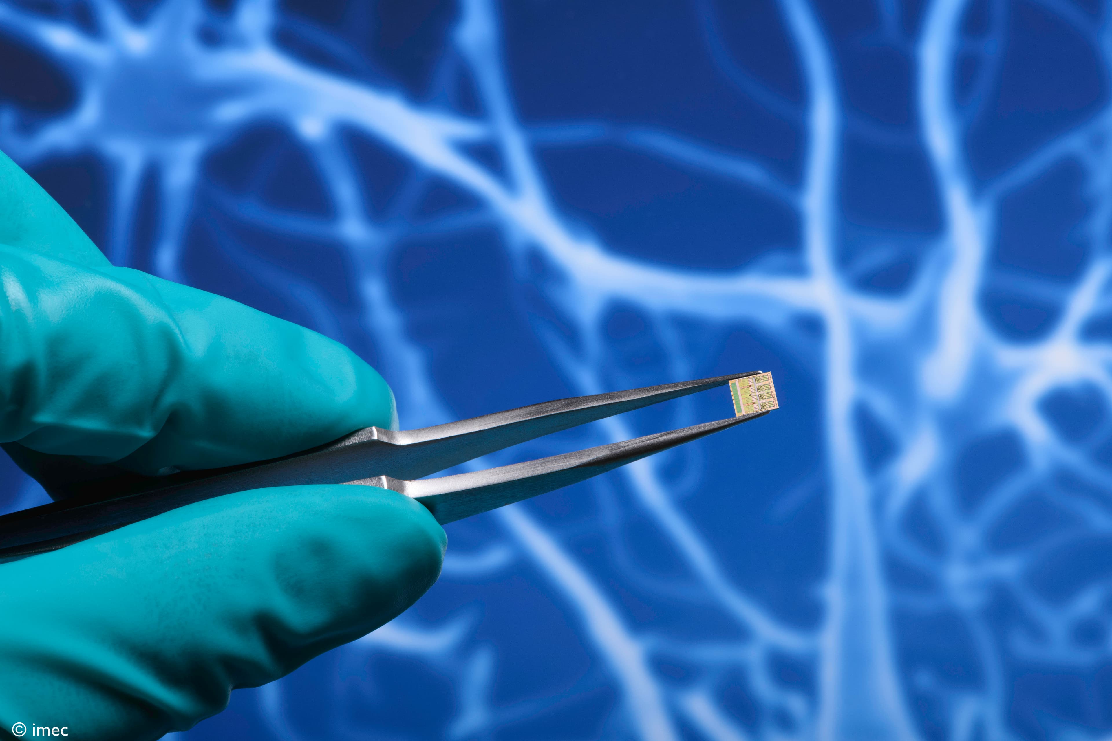 _VBW.0124.0706_Neuromodulation-%20Ignite Gloved hand holding a tiny microchip with tweezers against a blue neural network background