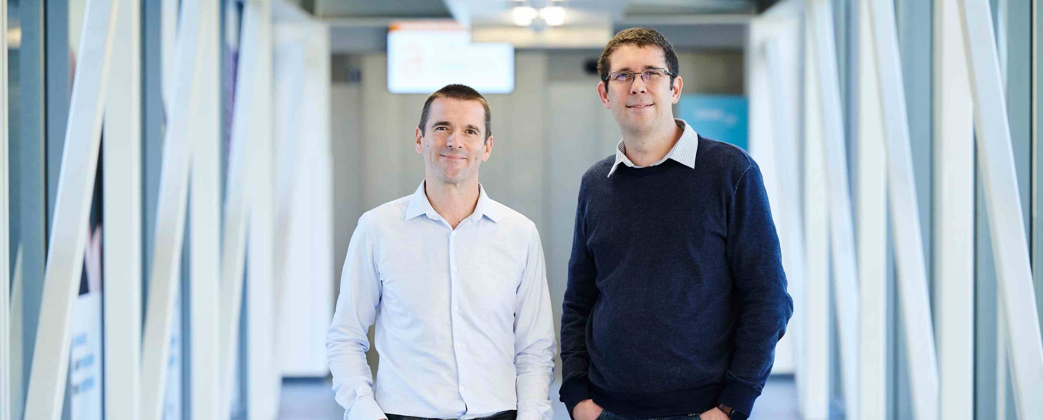 Two men standing in a modern corridor Two men standing in a modern corridor, likely company founders or executives