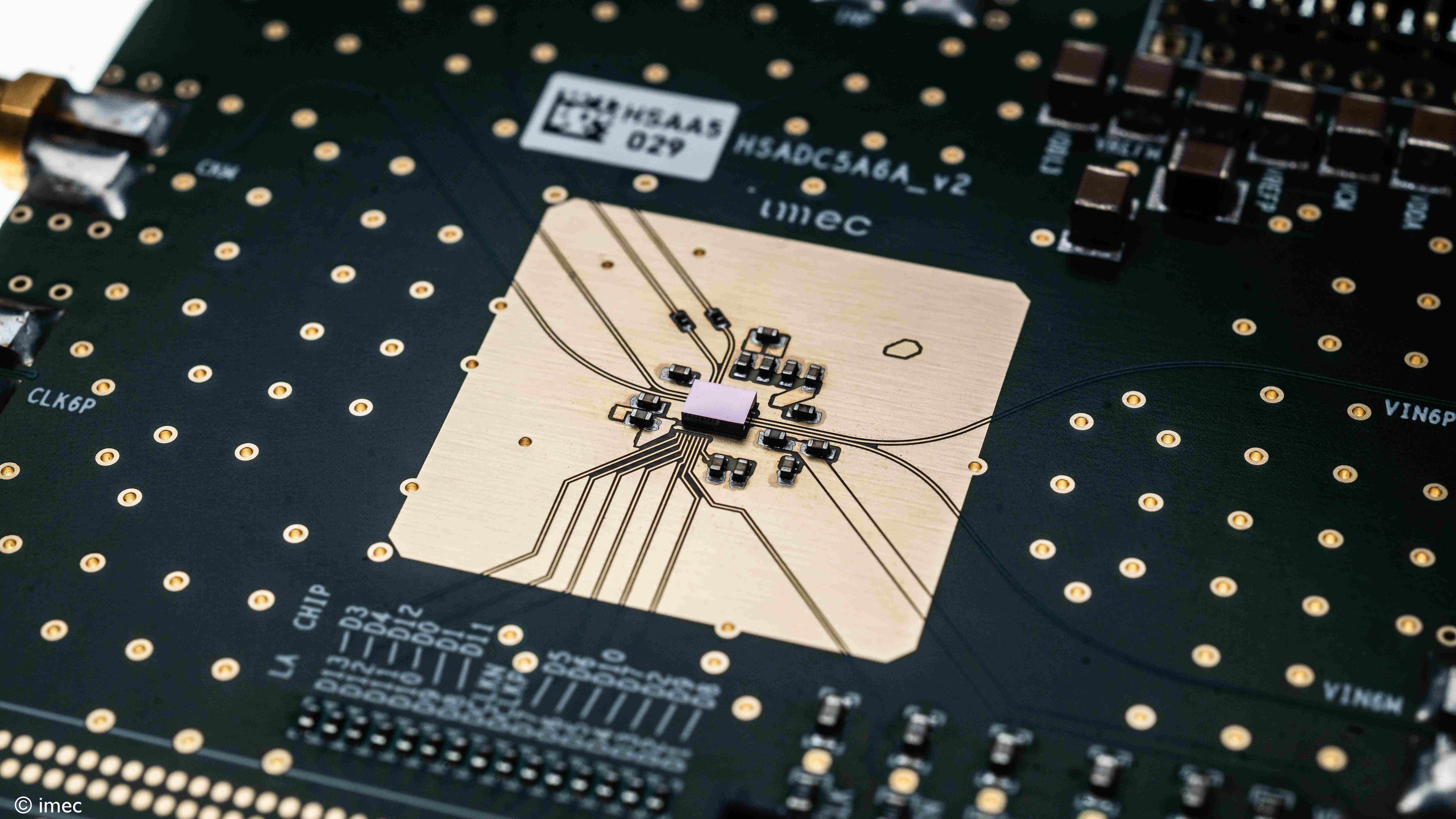 VLSI-%26-RFIC-persbericht-foto%27s006_1 Close-up of an imec chip test board with a central semiconductor package and wire bonds.