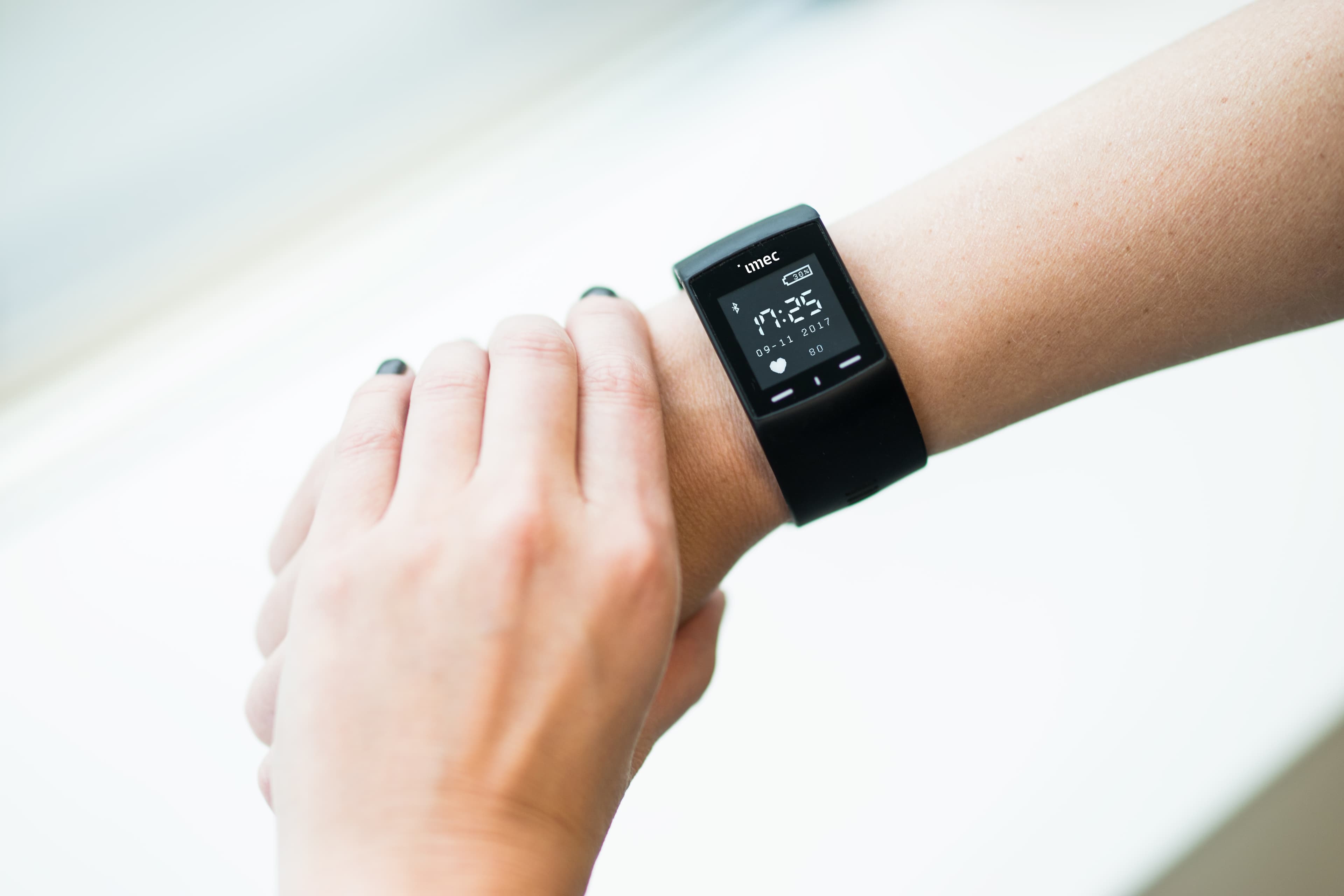Hand adjusting imec wristband on wrist Hand adjusting an imec wristband wearable on a person’s wrist