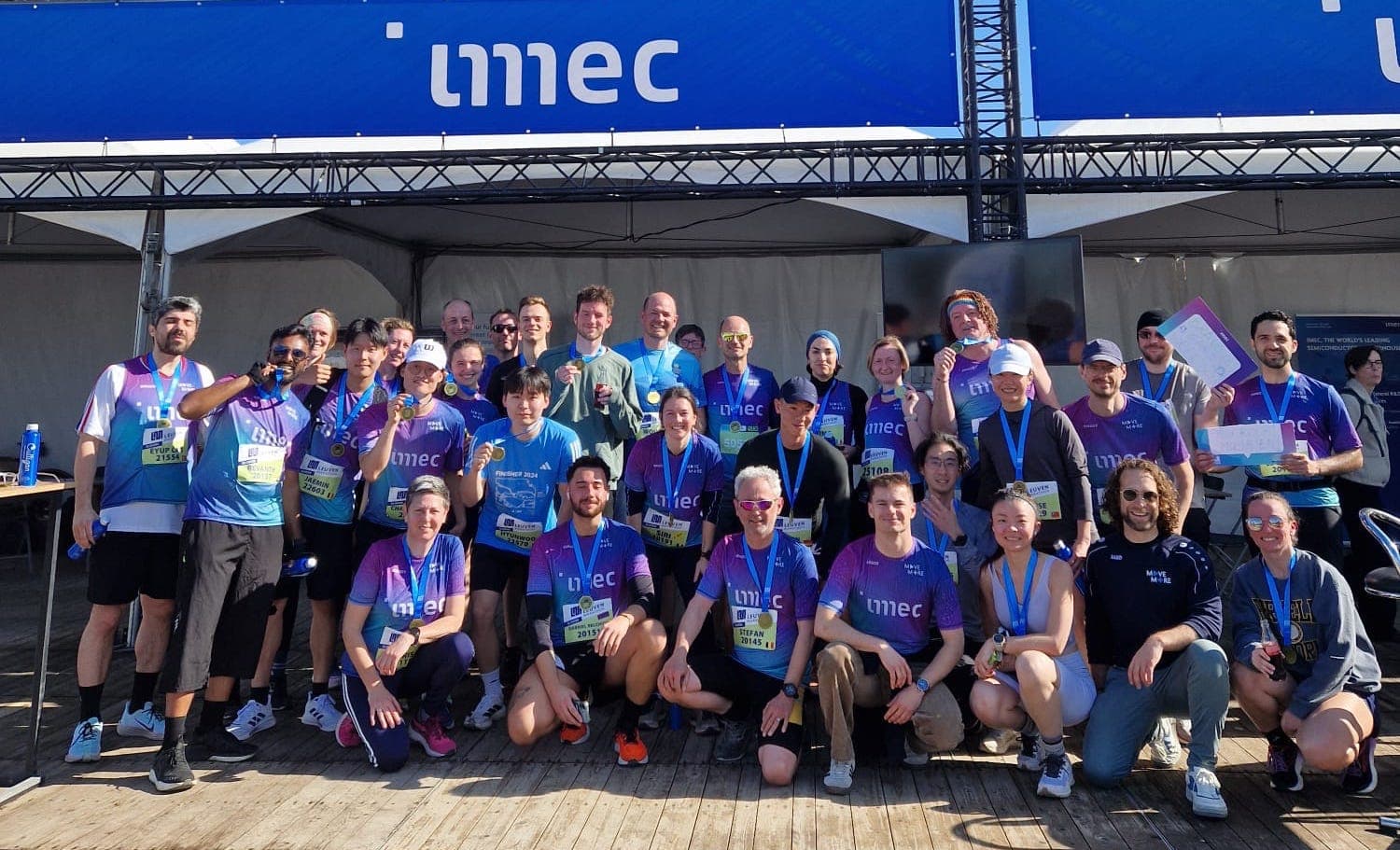 We%20care%20about%20the%20way%20you%20move Imec employees posing with medals at a running event booth