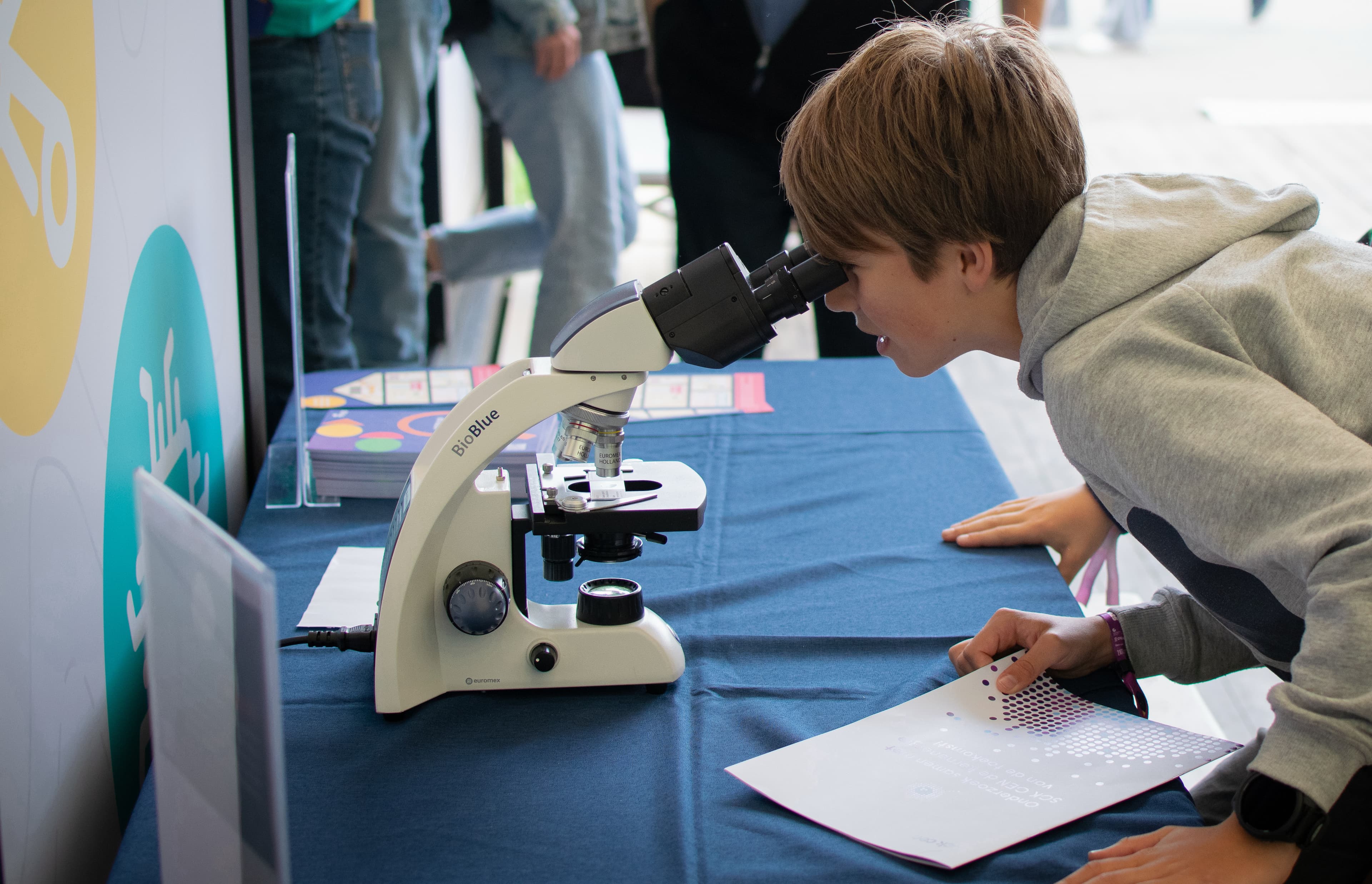 We%20care%20about%20your%20family Child looking through a microscope at a science exhibit table
