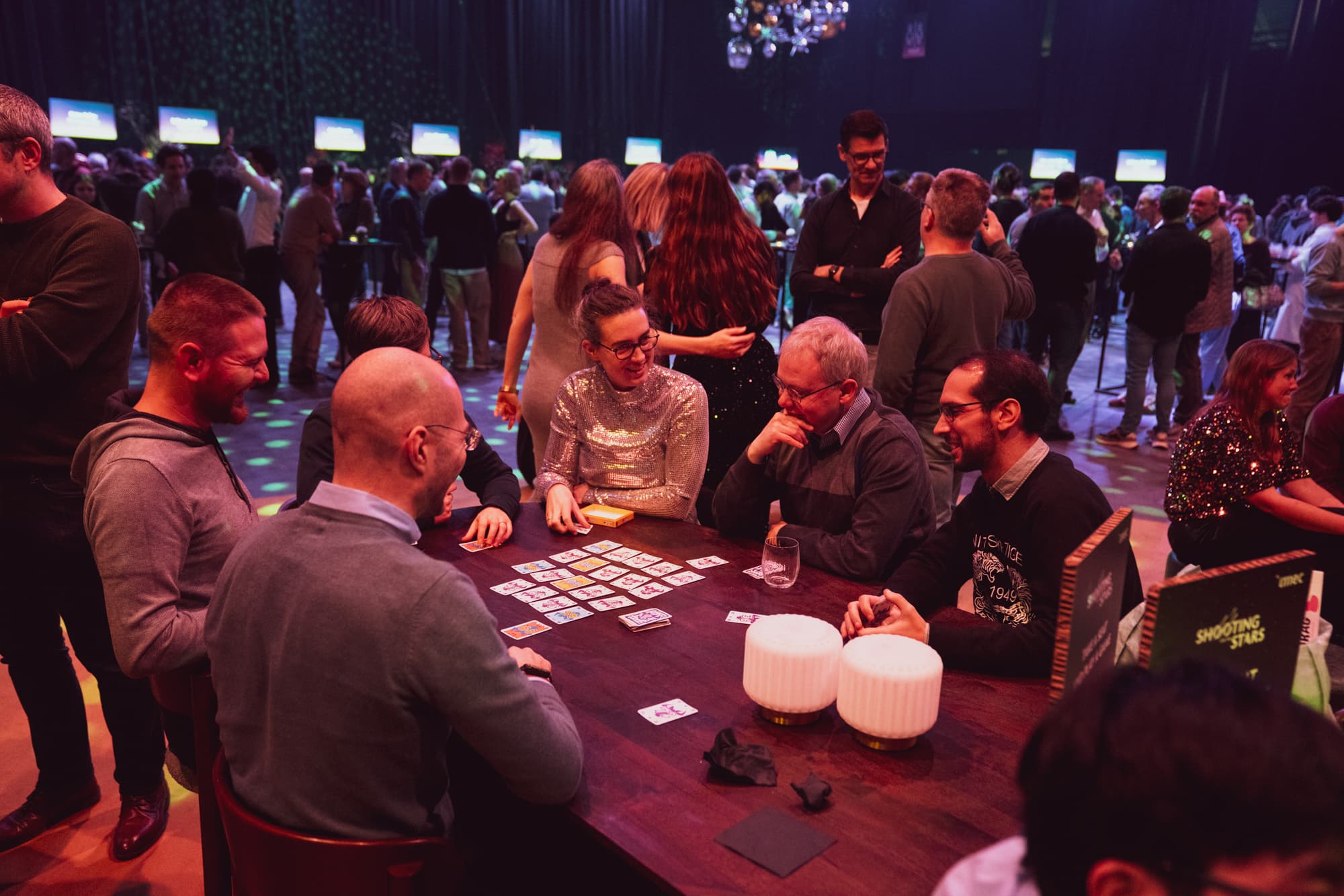 We%20care%20about%20your%20time Colleagues chatting and playing cards at a lively imec social event