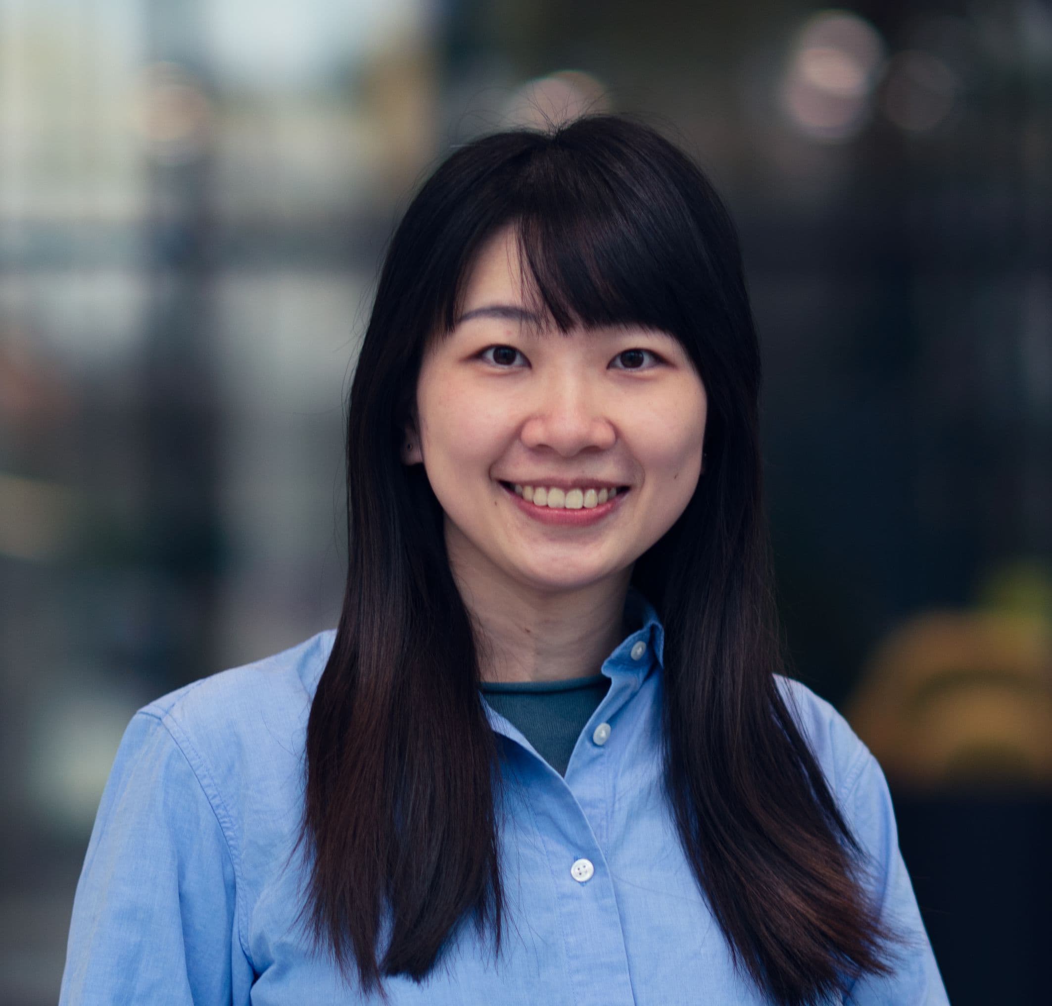 Wen-Chieh%20Chen_2 Portrait of Wen-Chieh Chen smiling in a light blue shirt against a blurred lab background