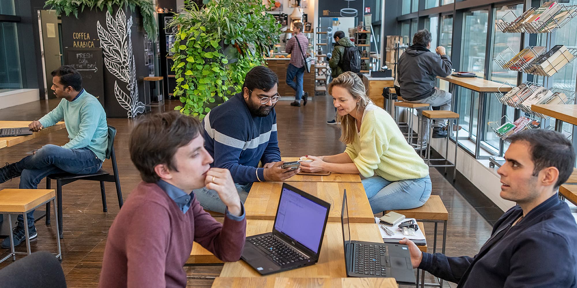 why-work-in-belgium_0 Imec employees and visitors working and chatting in a bright café lounge with laptops