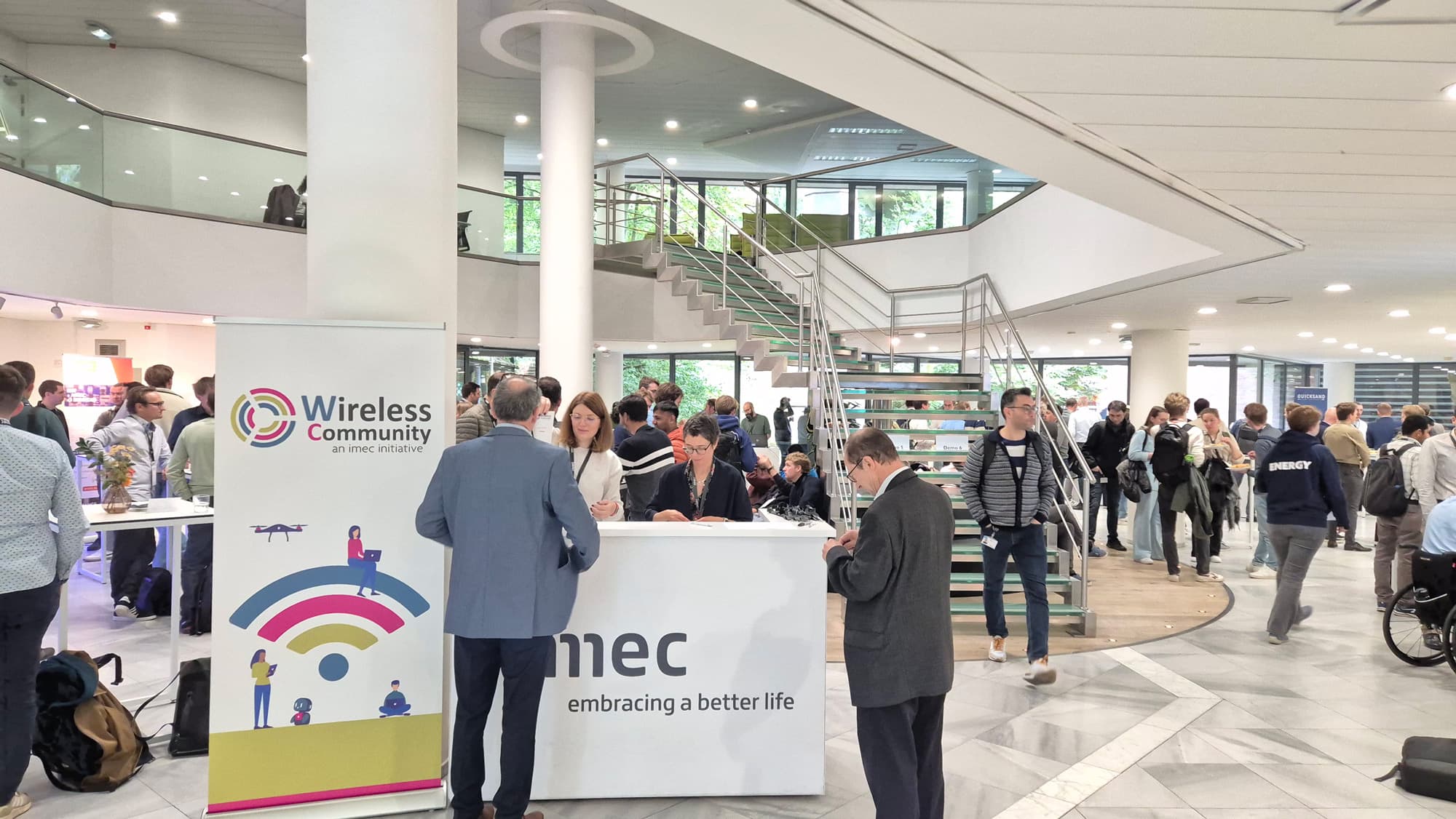 Wireless-community Bezoekers mengen zich bij de stand van het Wireless Community-evenement in de lobby van imec