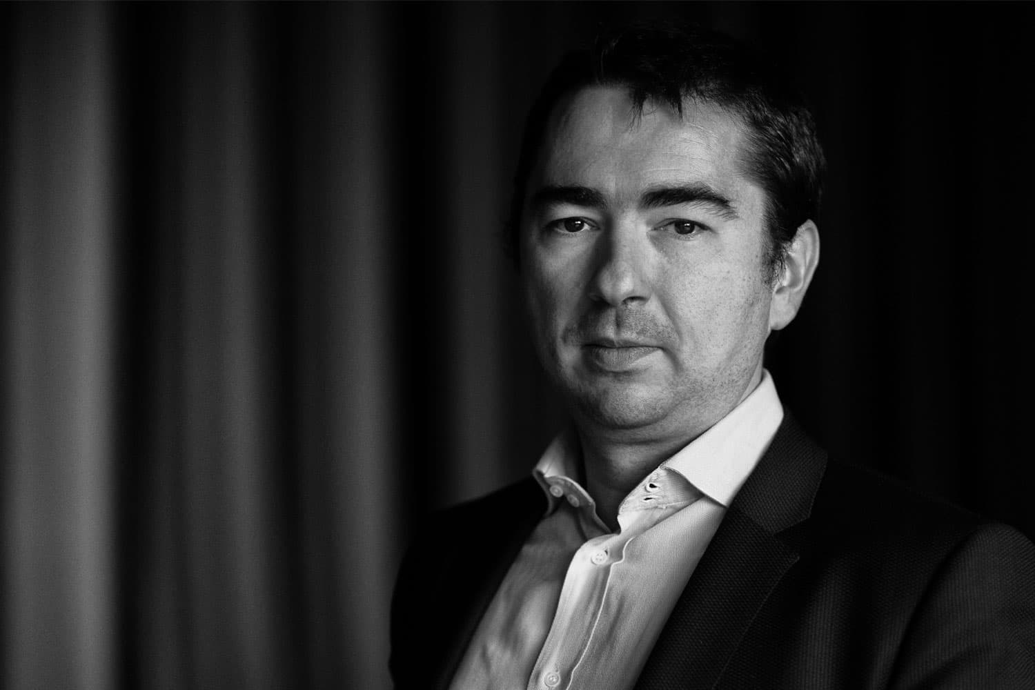 Xavier_Rottenberg Black-and-white portrait of Xavier Rottenberg in a suit and open-collar shirt
