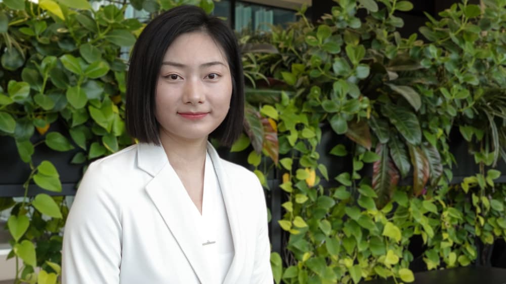 Xinyue-Chang Xinyue Chang, a Ph.D. researcher, standing in front of a leafy green wall