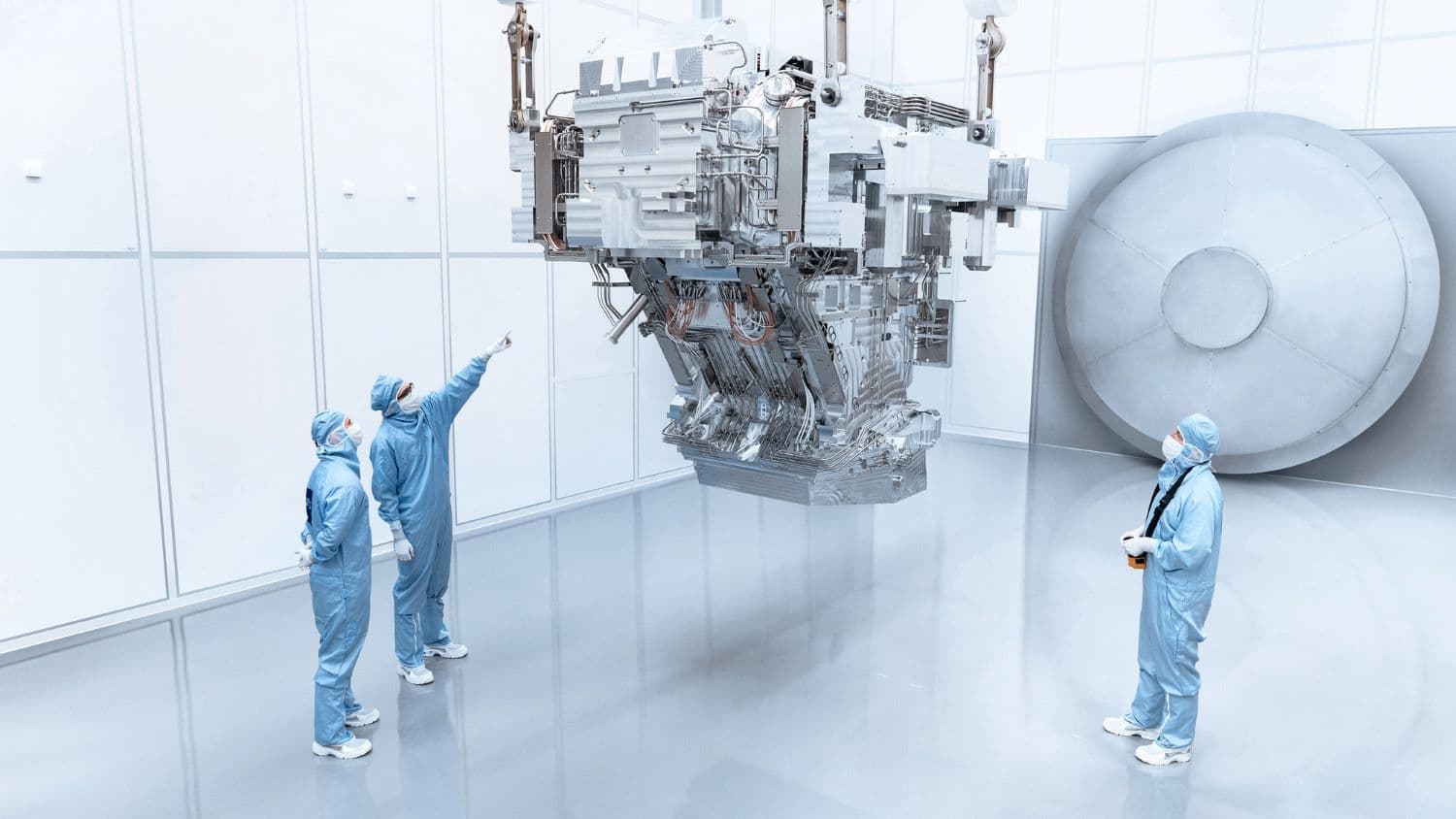zeiss-illumination-system-for-high-na-euv-lithography Cleanroom researchers inspect a large EUV lithography system in a bright white laboratory.