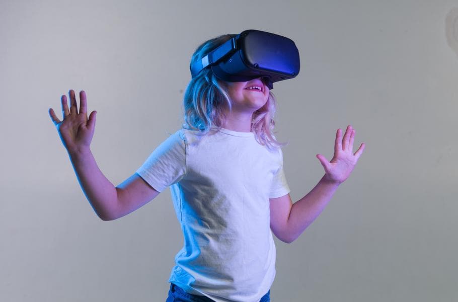 Zoe_0 Child wearing a VR headset with hands raised against a plain background
