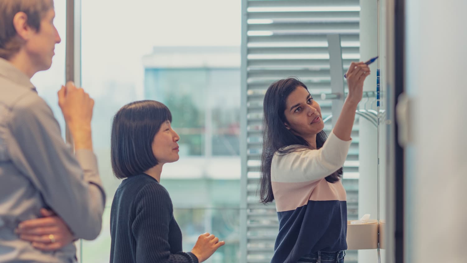 Difference Colleagues collaborating at a whiteboard in a bright office
