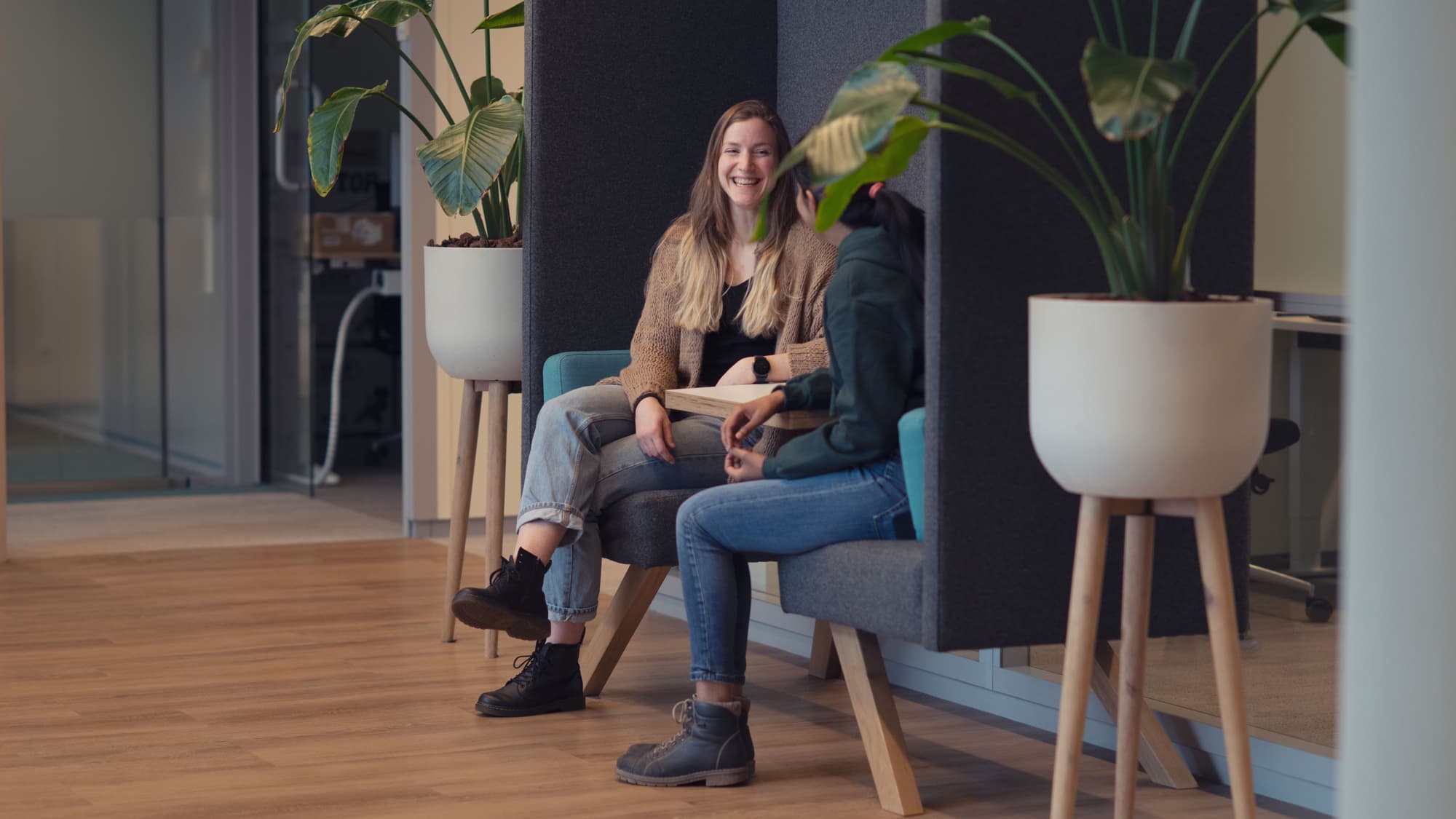 Educational-cooperation Two students talking in a modern office lounge with indoor plants